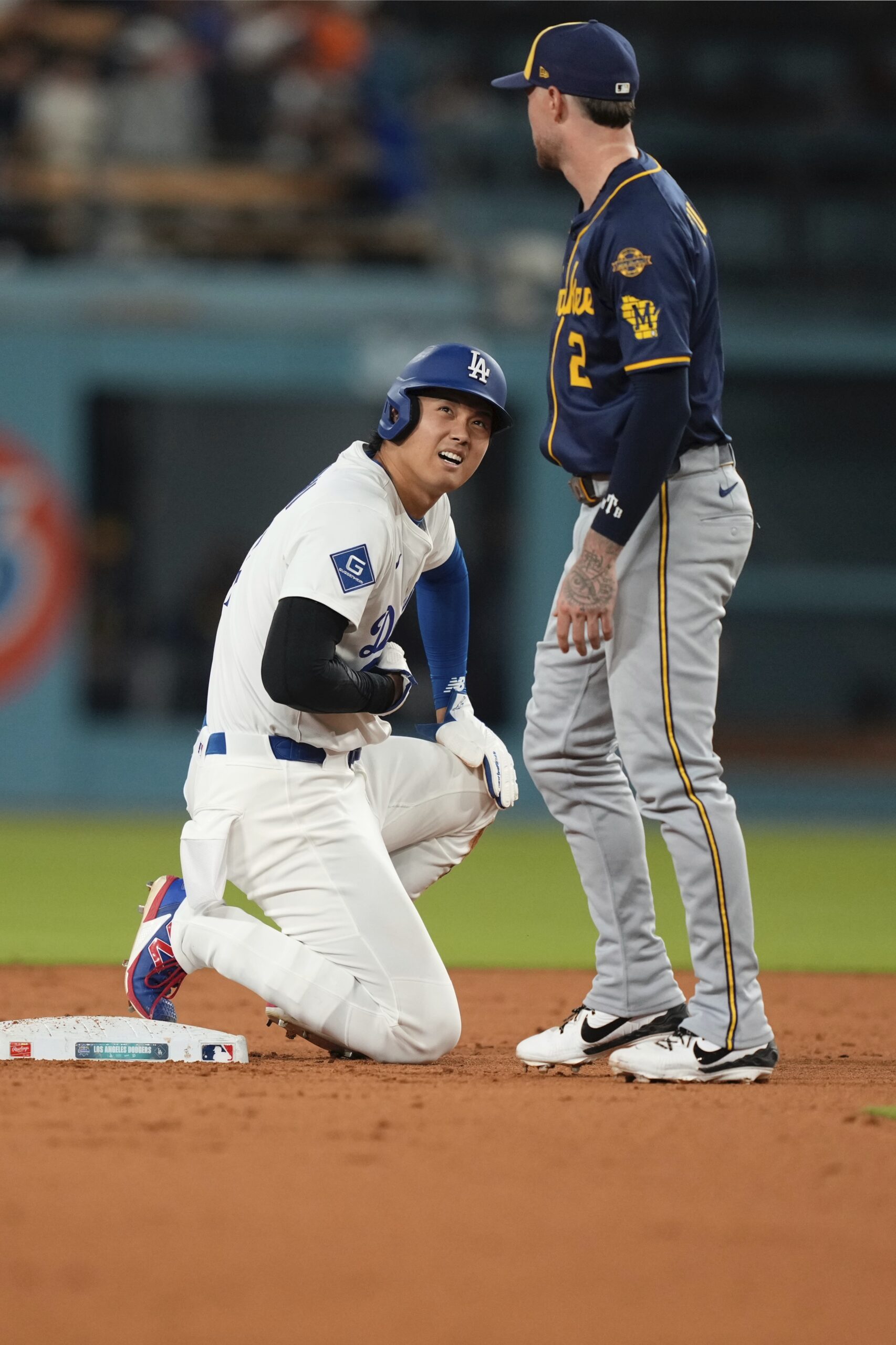 Dodgers star Shohei Ohtani, left, winces after colliding with Milwaukee...