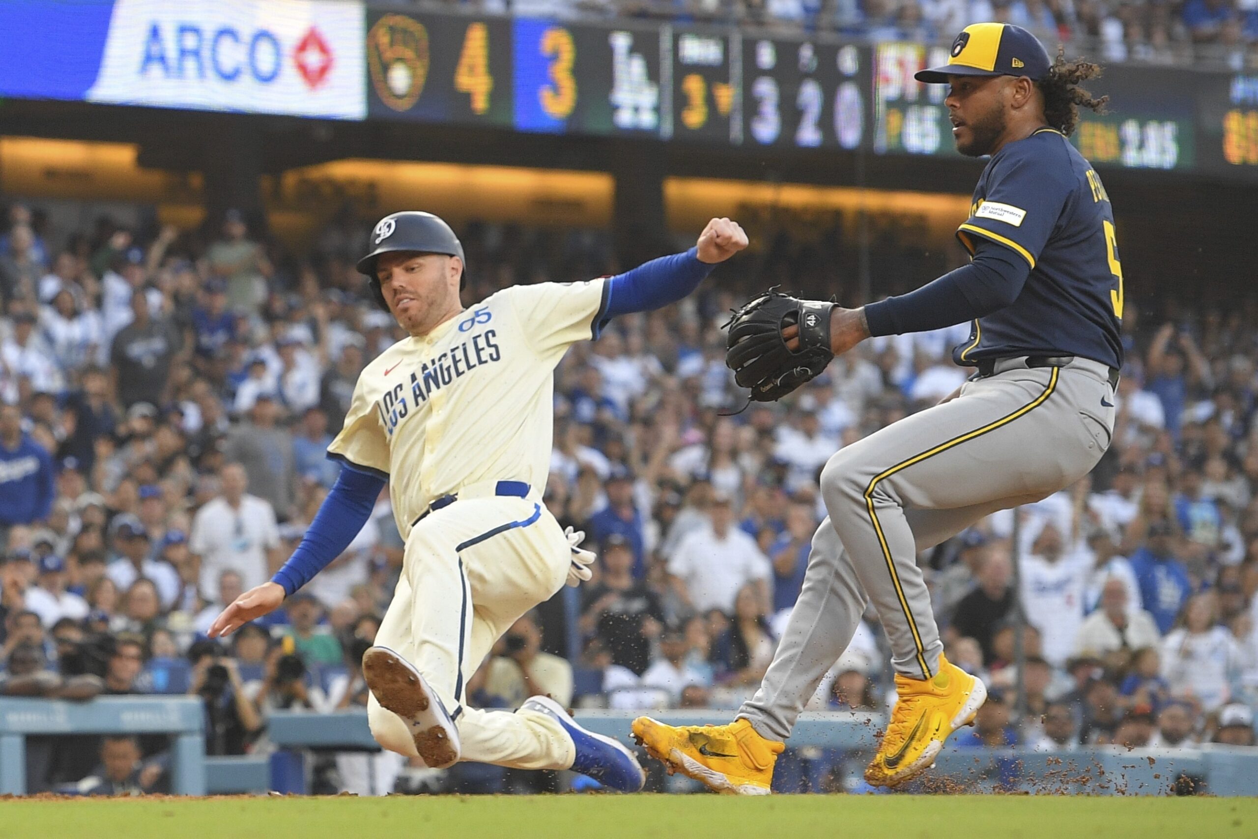 Dodgers’ Freddie Freeman, left, scores on a wild pitch by...