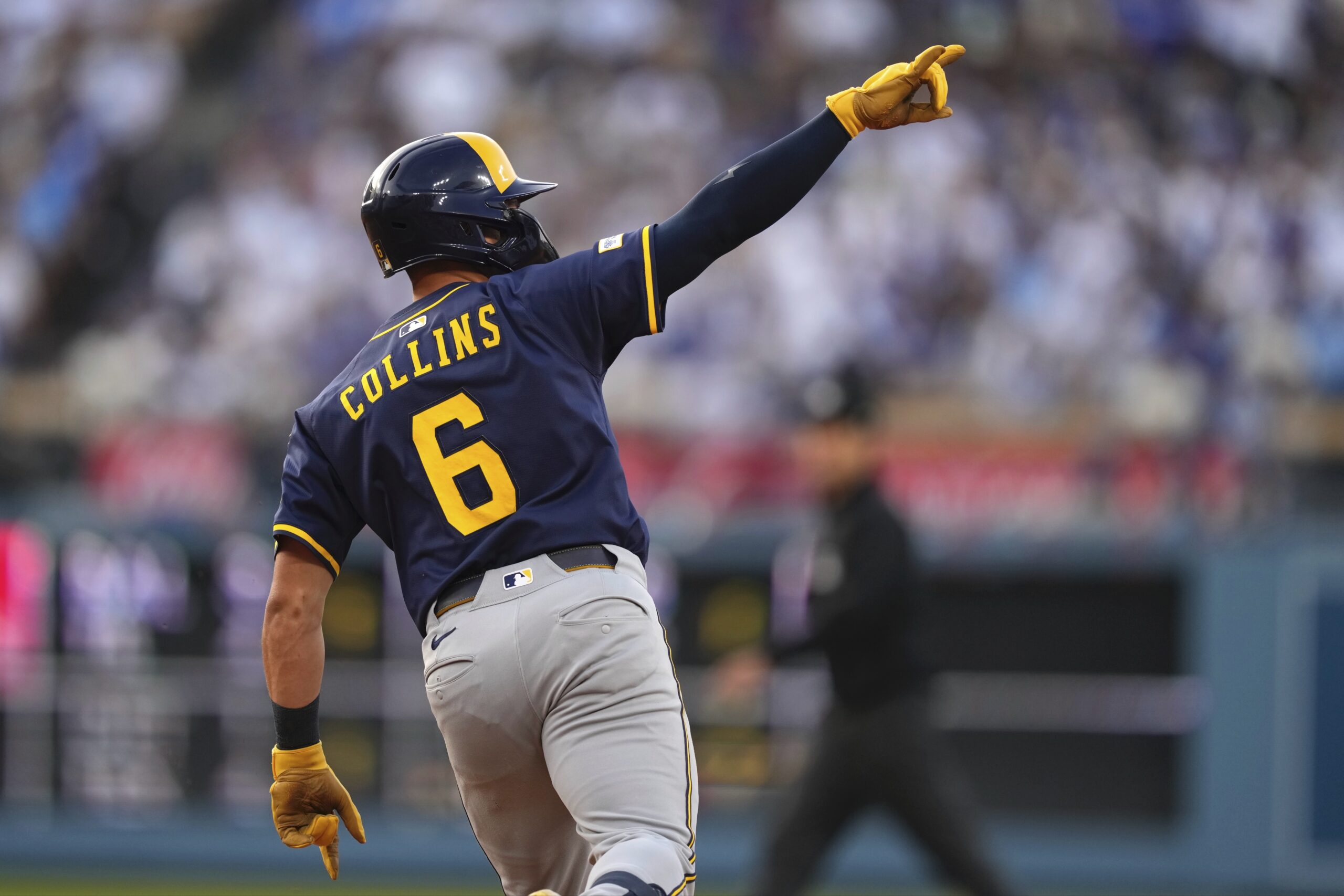 Milwaukee Brewers’ Isaac Collins gestures as he rounds first after...