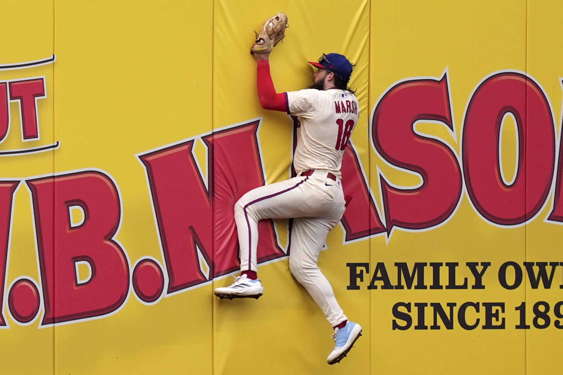 Philadelphia Phillies center fielder Brandon Marsh collides with the wall...