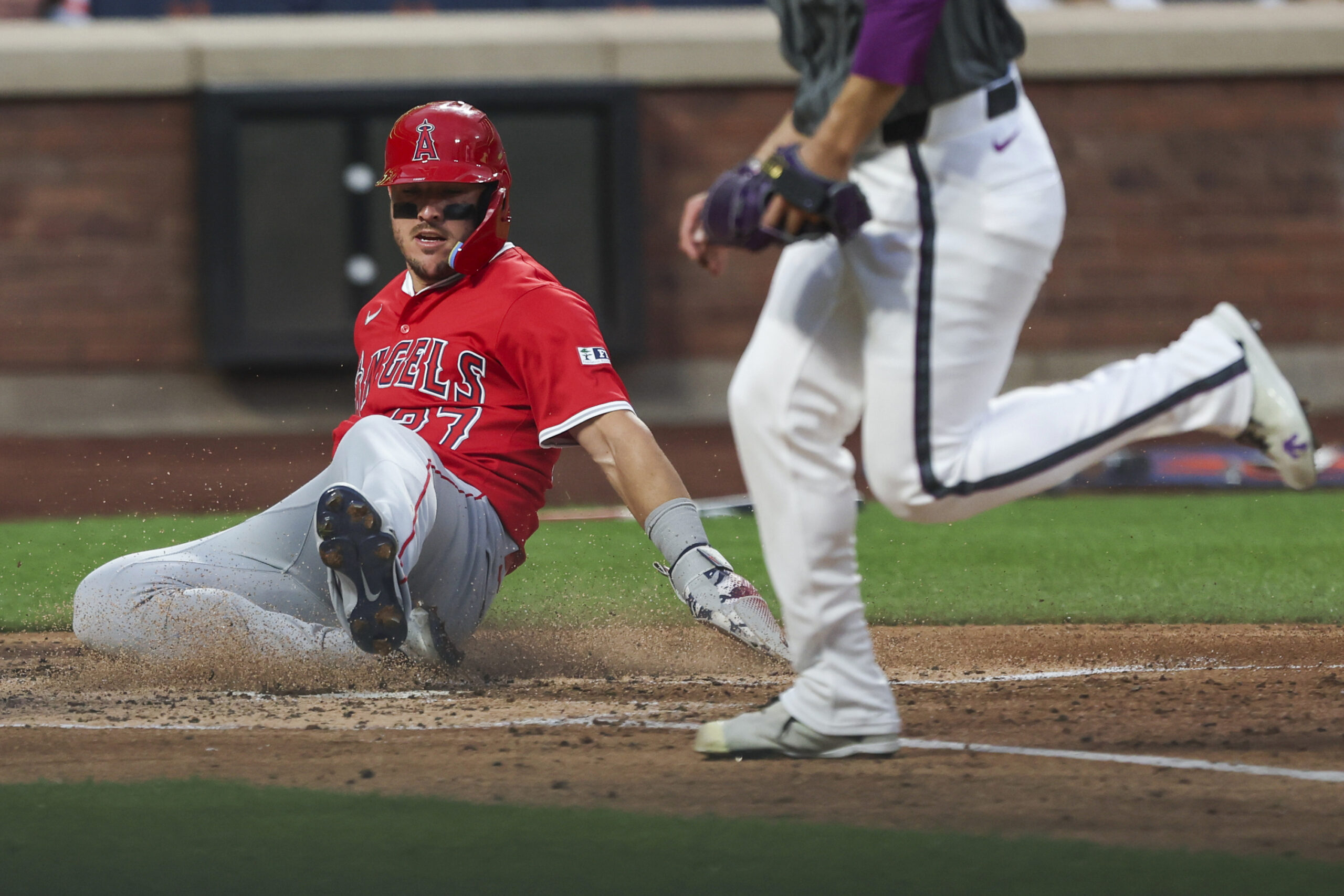 Angels star Mike Trout, left, slides home to score during...