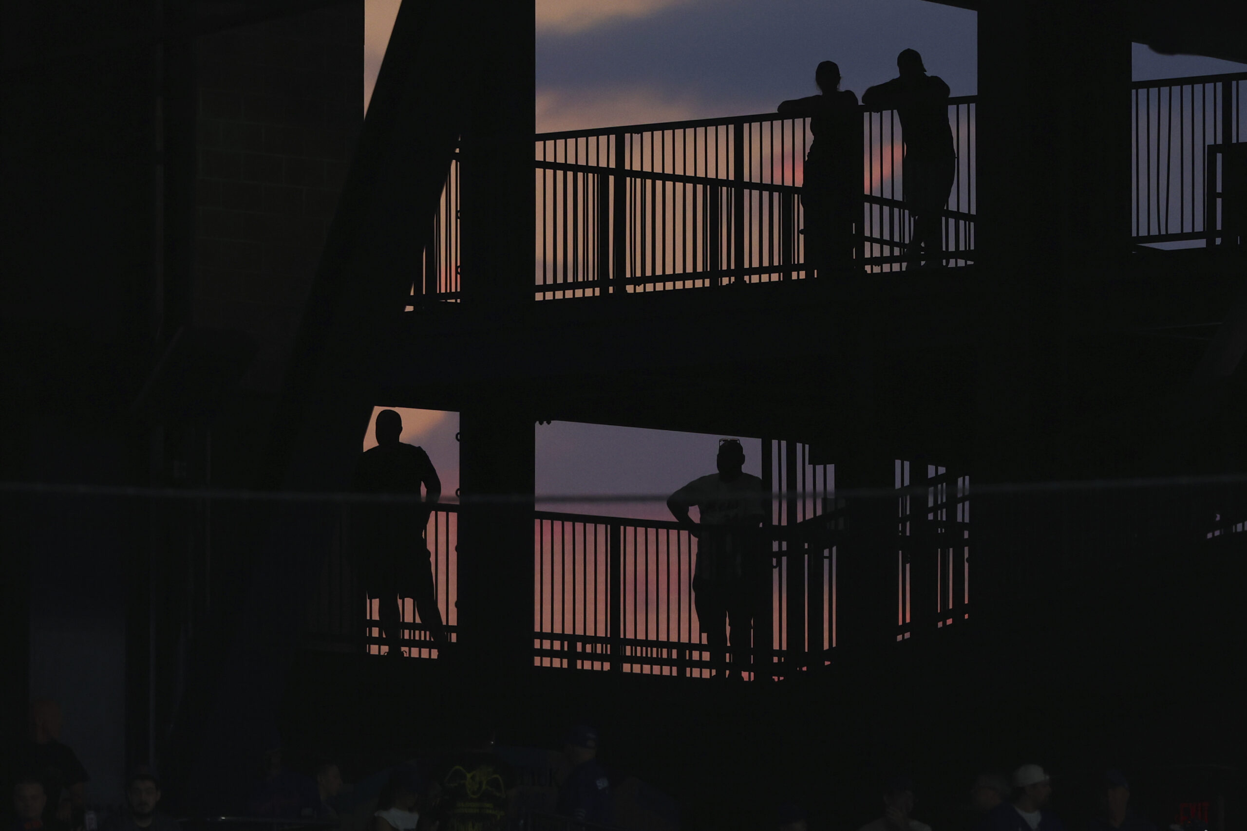 Fans are silhouetted against the sunset while taking in a...