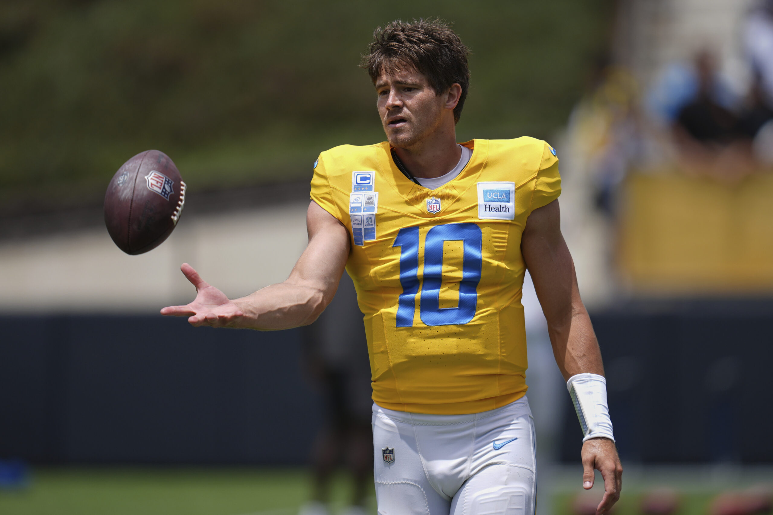 Chargers quarterback Justin Herbert catches a ball as he goes...