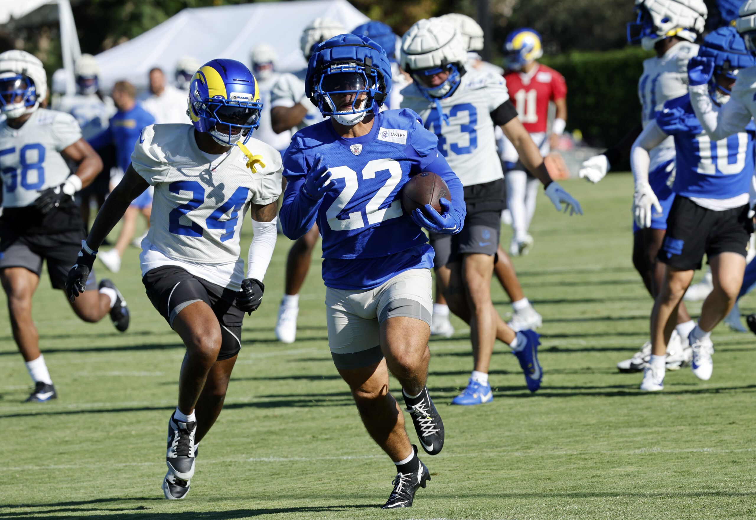 Rams running back Blake Corum, center, tries too outrun cornerback...