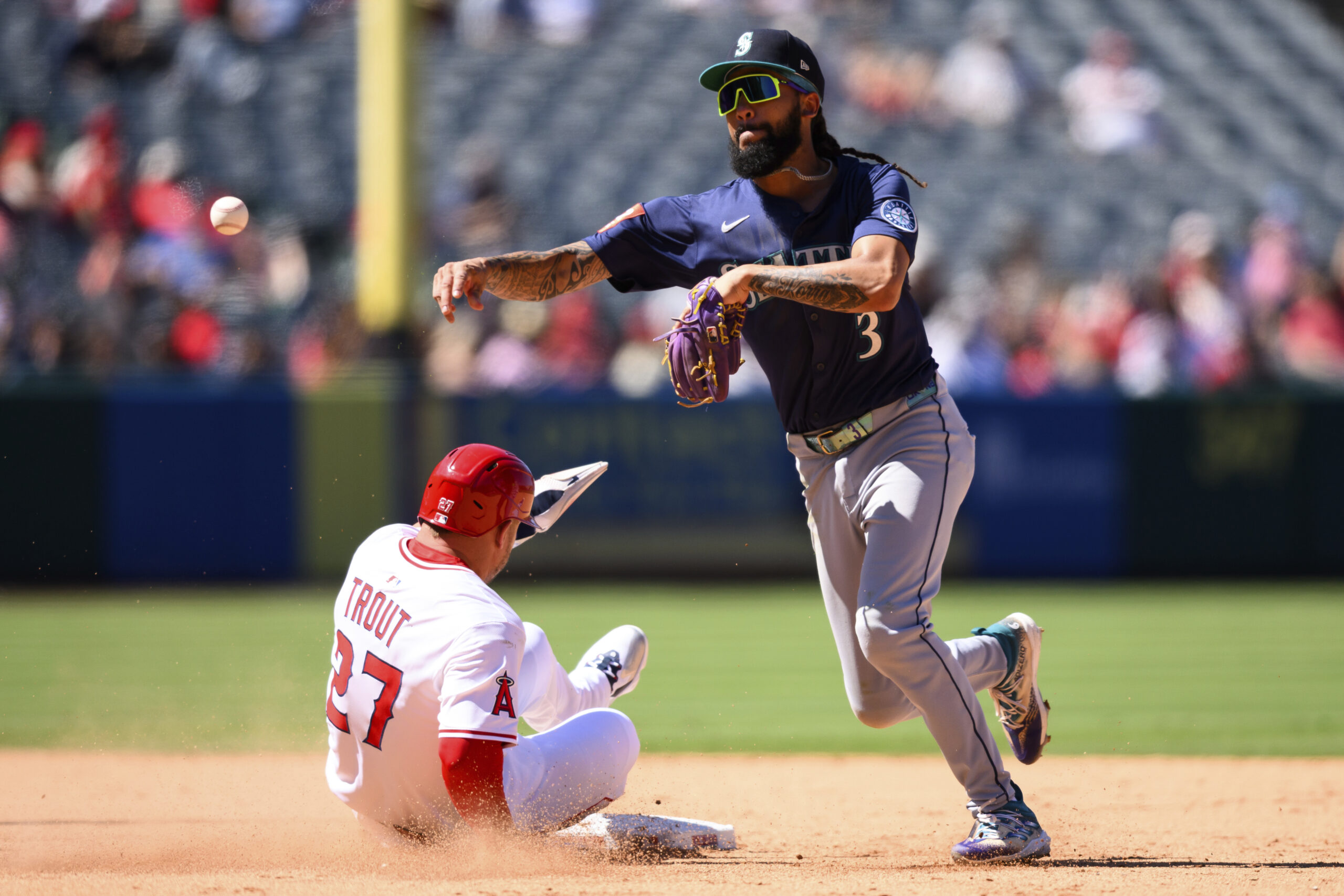 Angels’ Mike Trout, left, is forced out by Seattle Mariners...