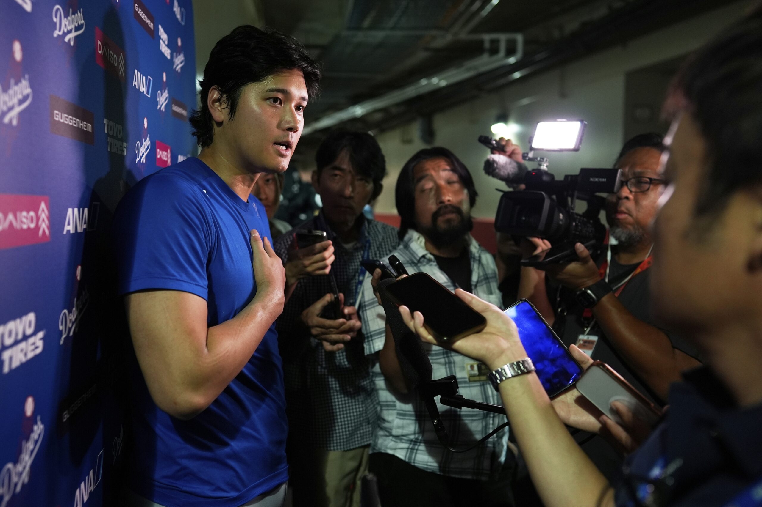 Dodgers star Shohei Ohtani talks to reporters after a game...