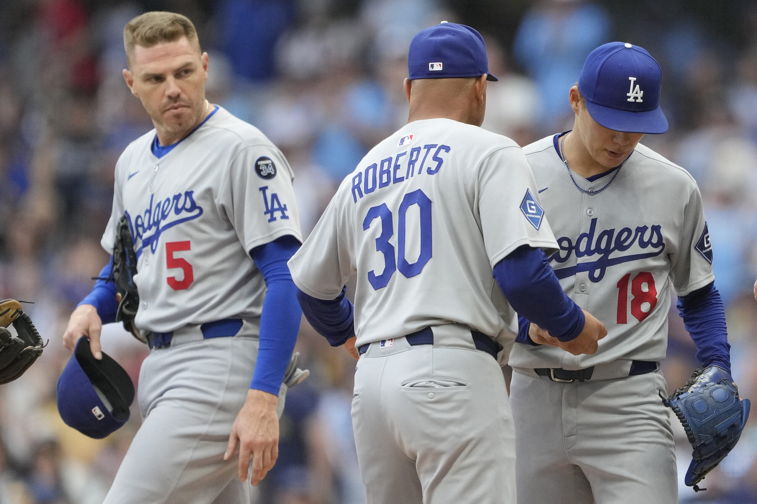 Dodgers starting pitcher Yoshinobu Yamamoto, right, hands the ball to...