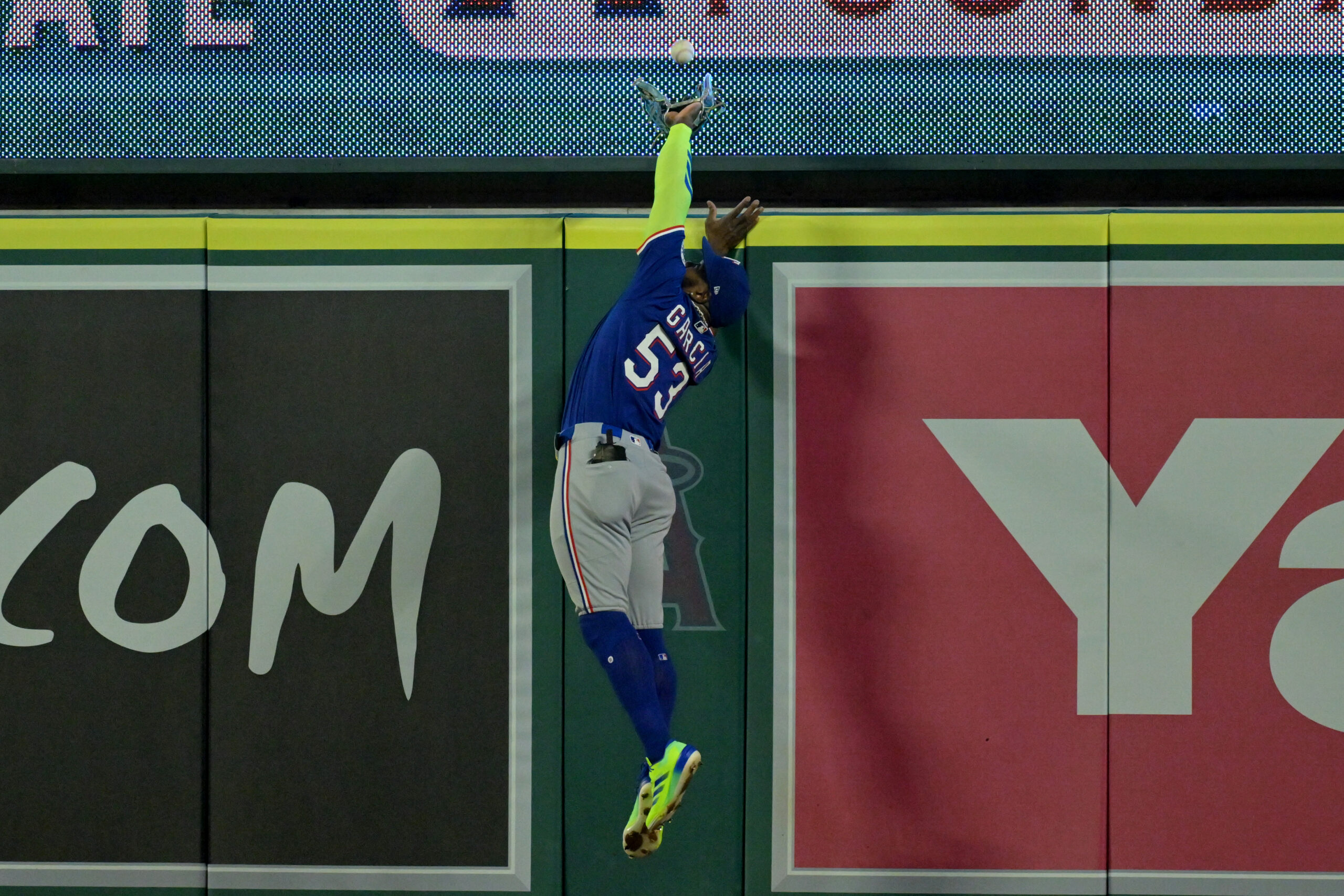 Texas Rangers right fielder Adolis Garcia reaches over the wall...