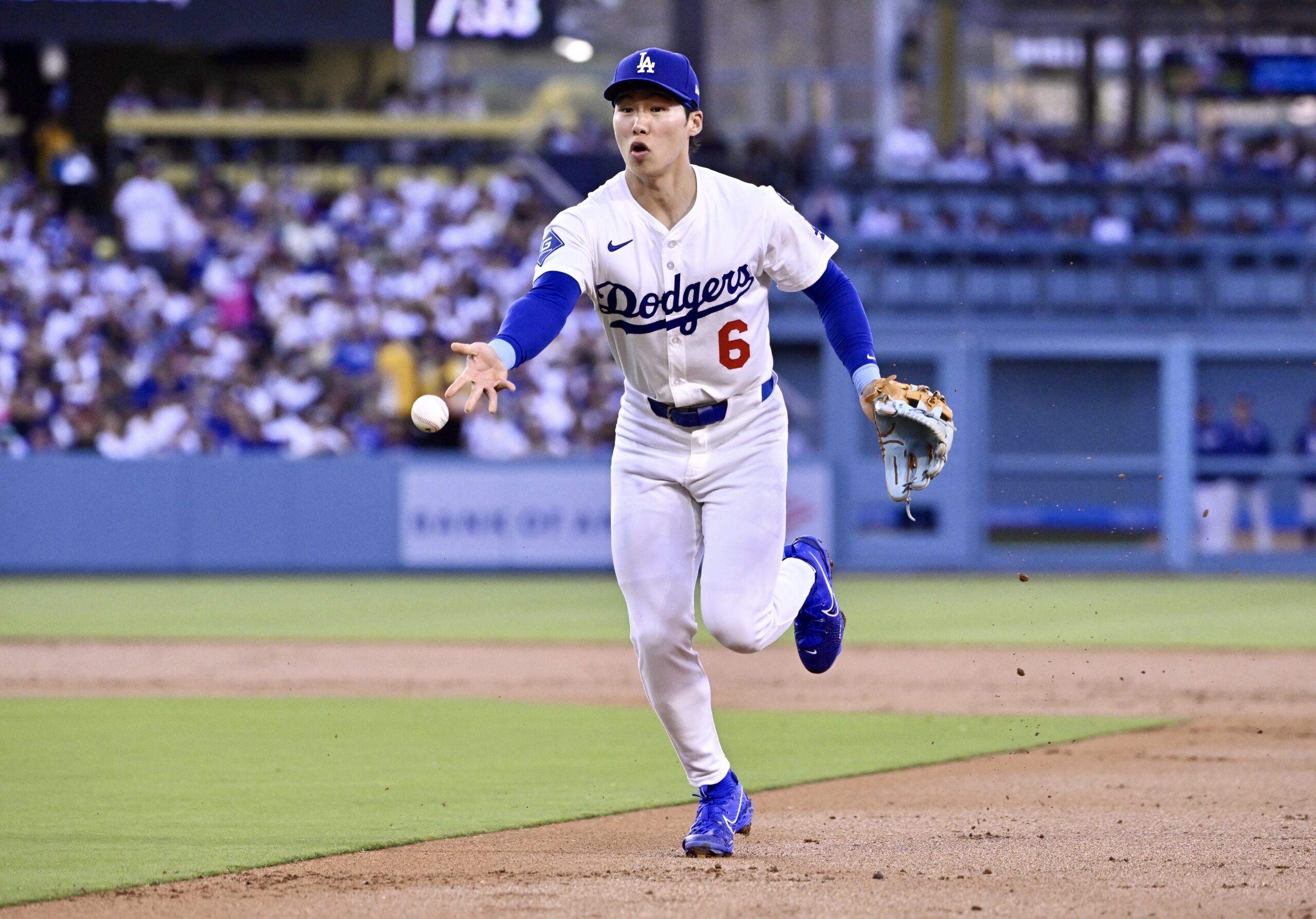 Dodgers second baseman Hyeseong Kim tosses the ball to first...