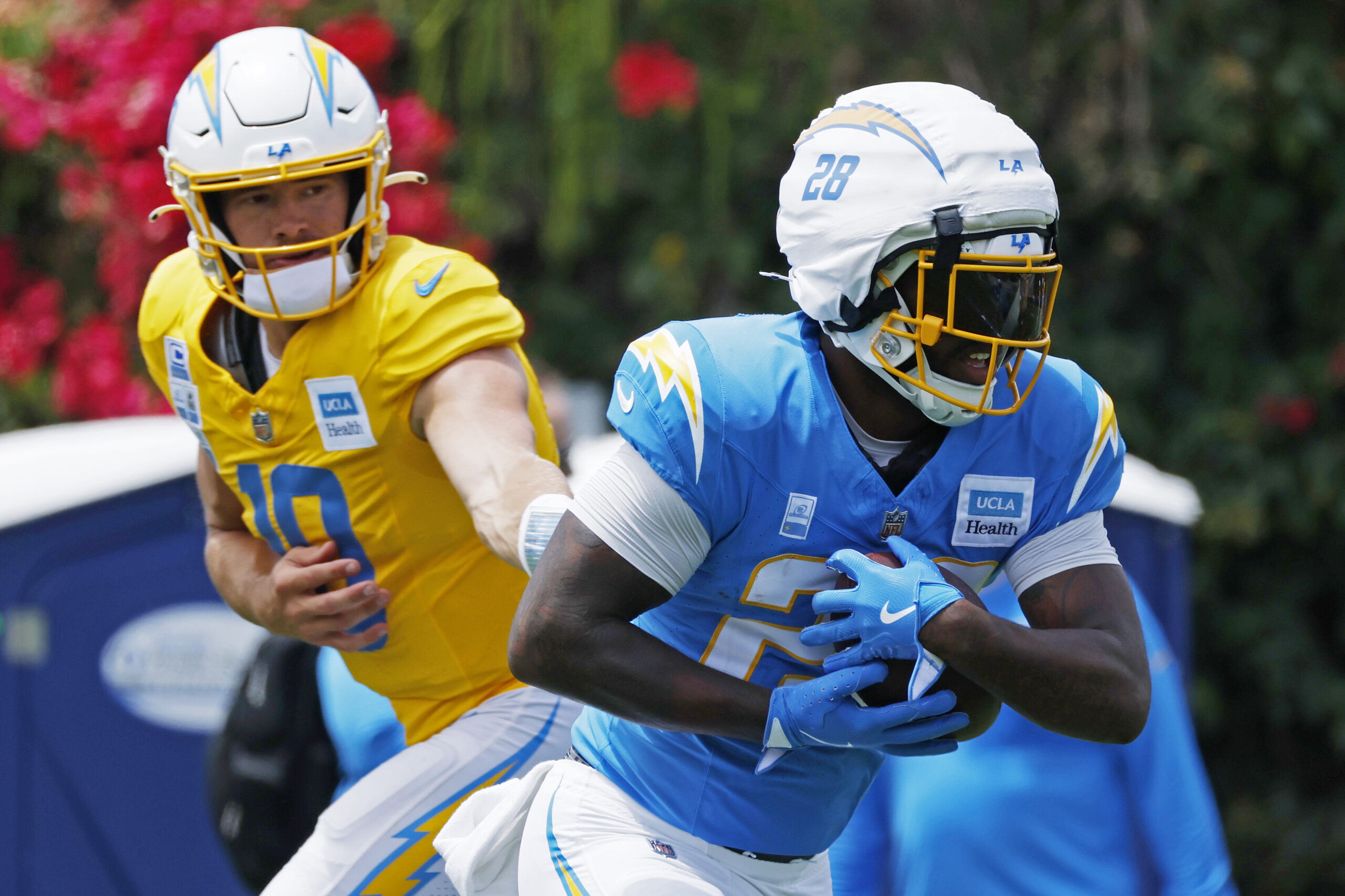 Chargers quarterback Justin Herbert, left, hands the ball off to...