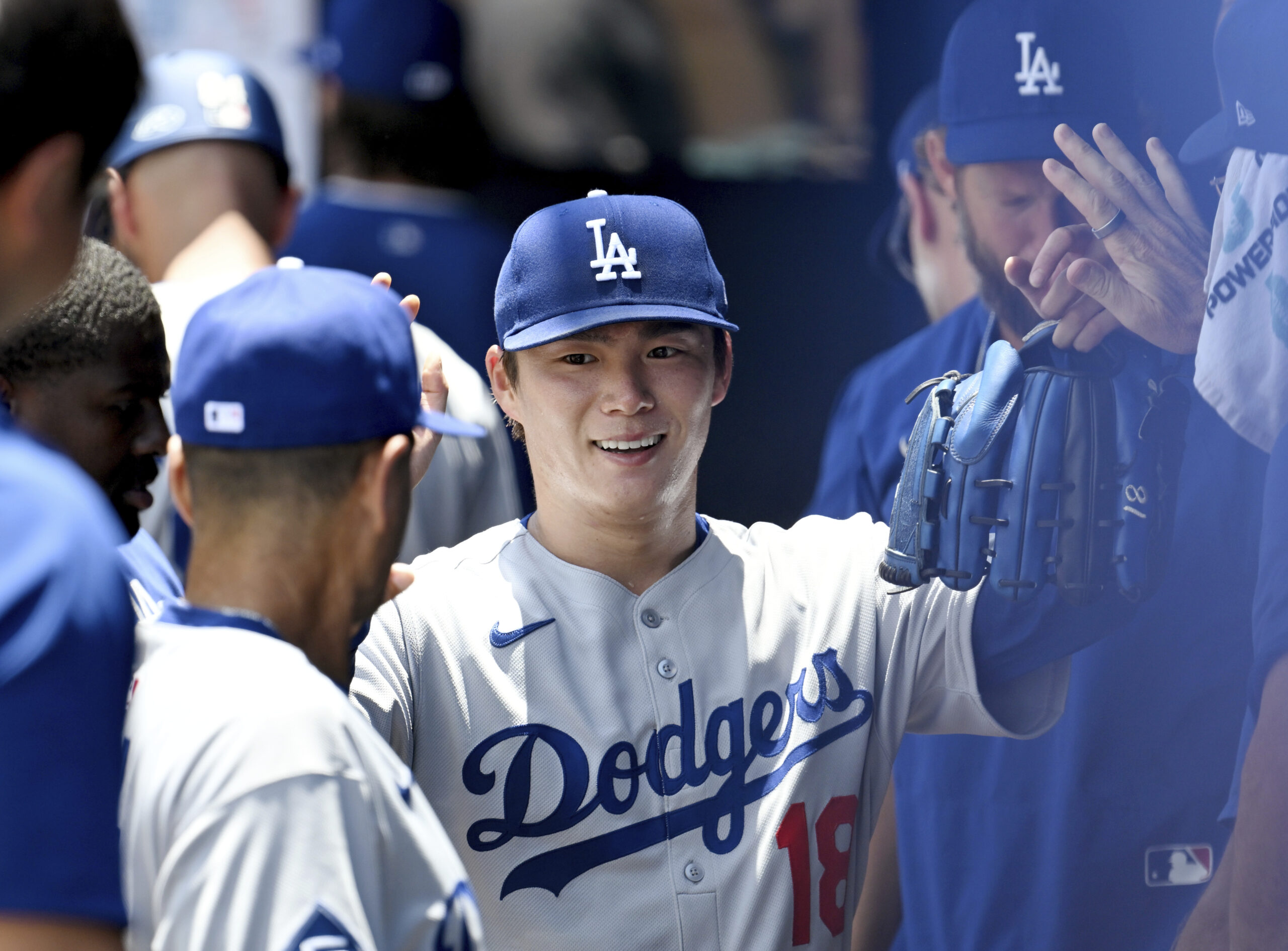 Dodgers pitcher Yoshinobu Yamamoto high fives teammates after coming out...