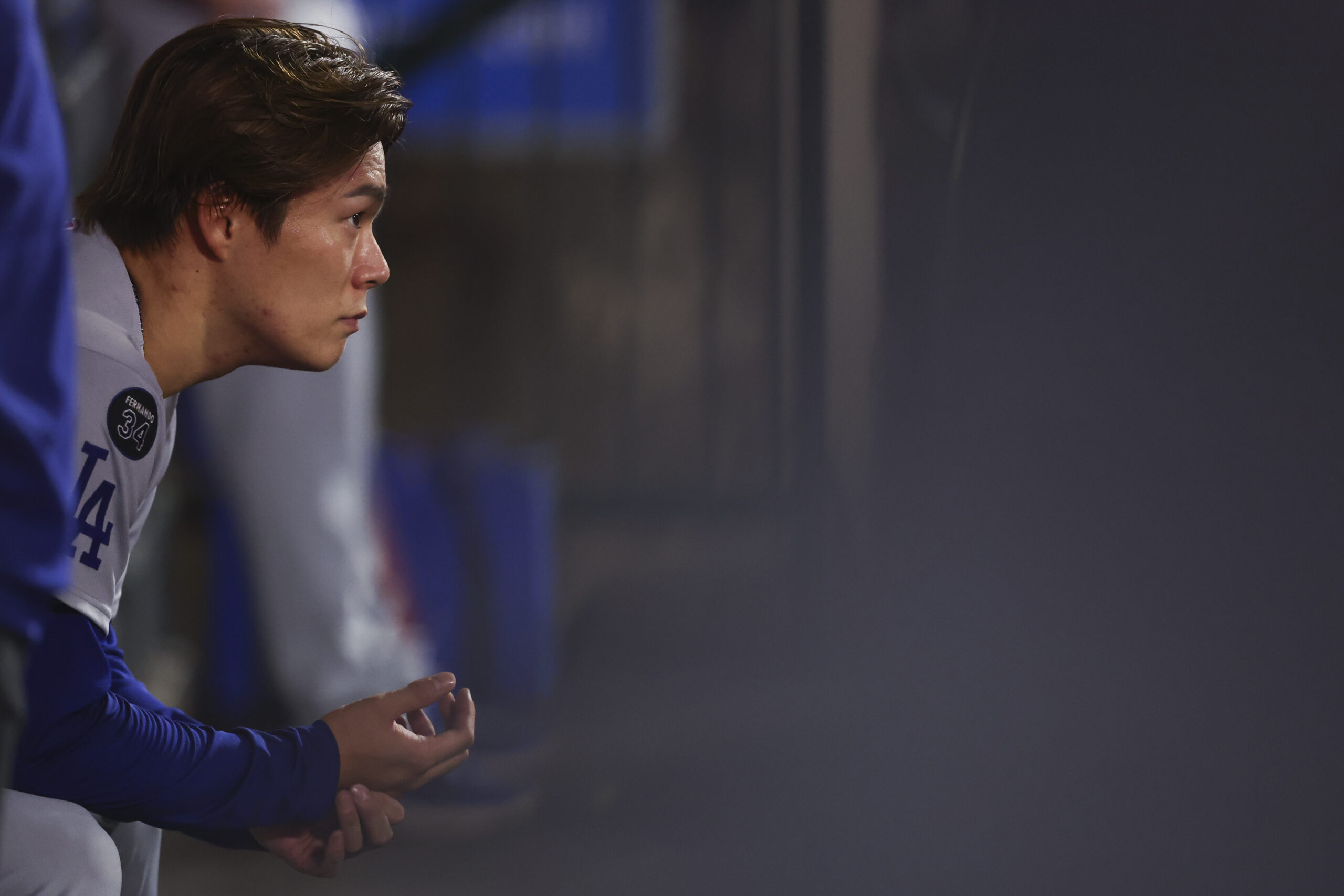 Dodgers starting pitcher Yoshinobu Yamamoto looks on from the dugout...