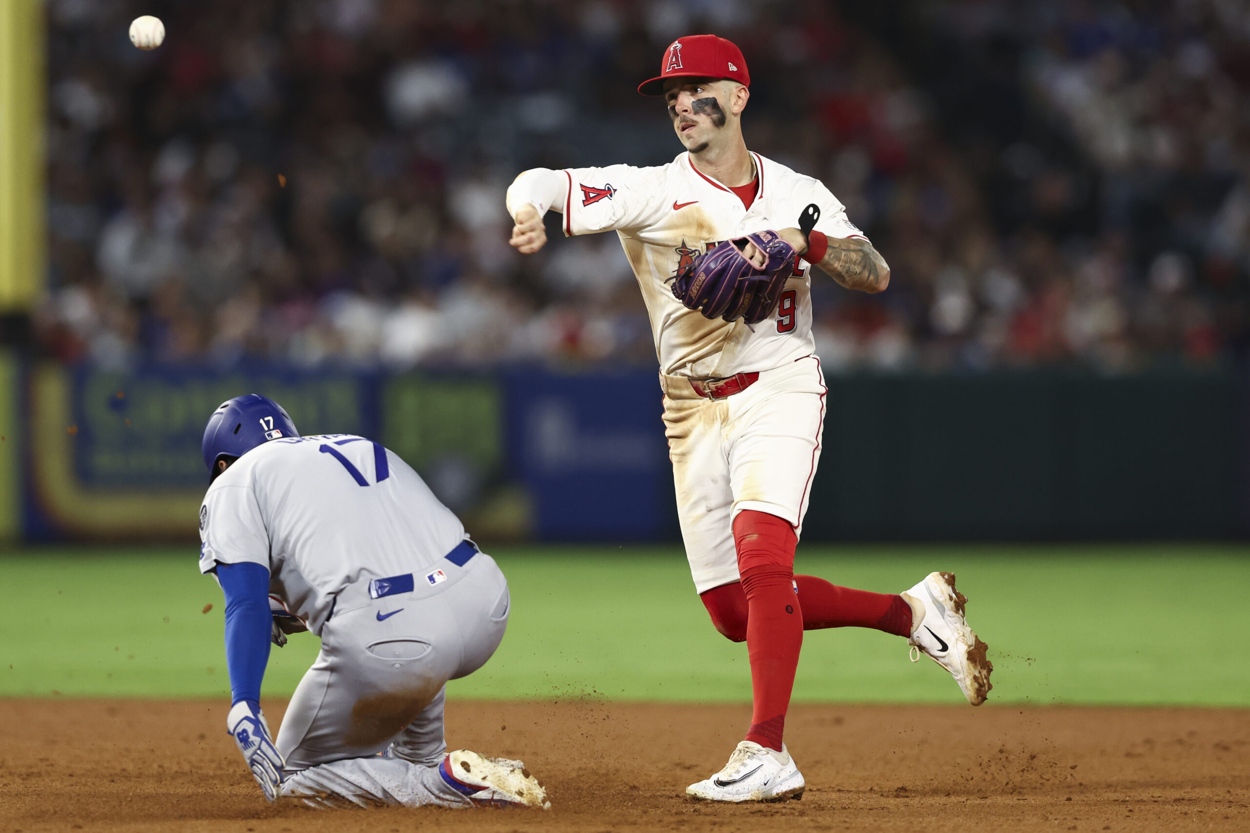 Angels shortstop Zach Neto throws to first base to complete...