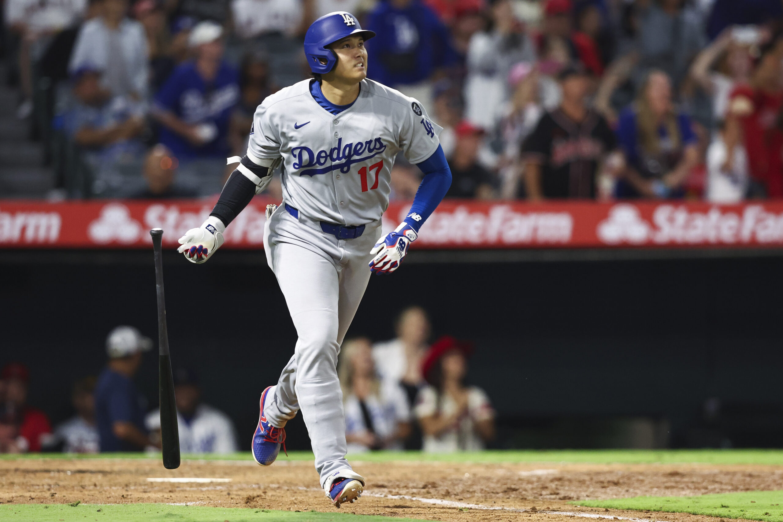 Dodgers star Shohei Ohtani drops his bat as he watches...