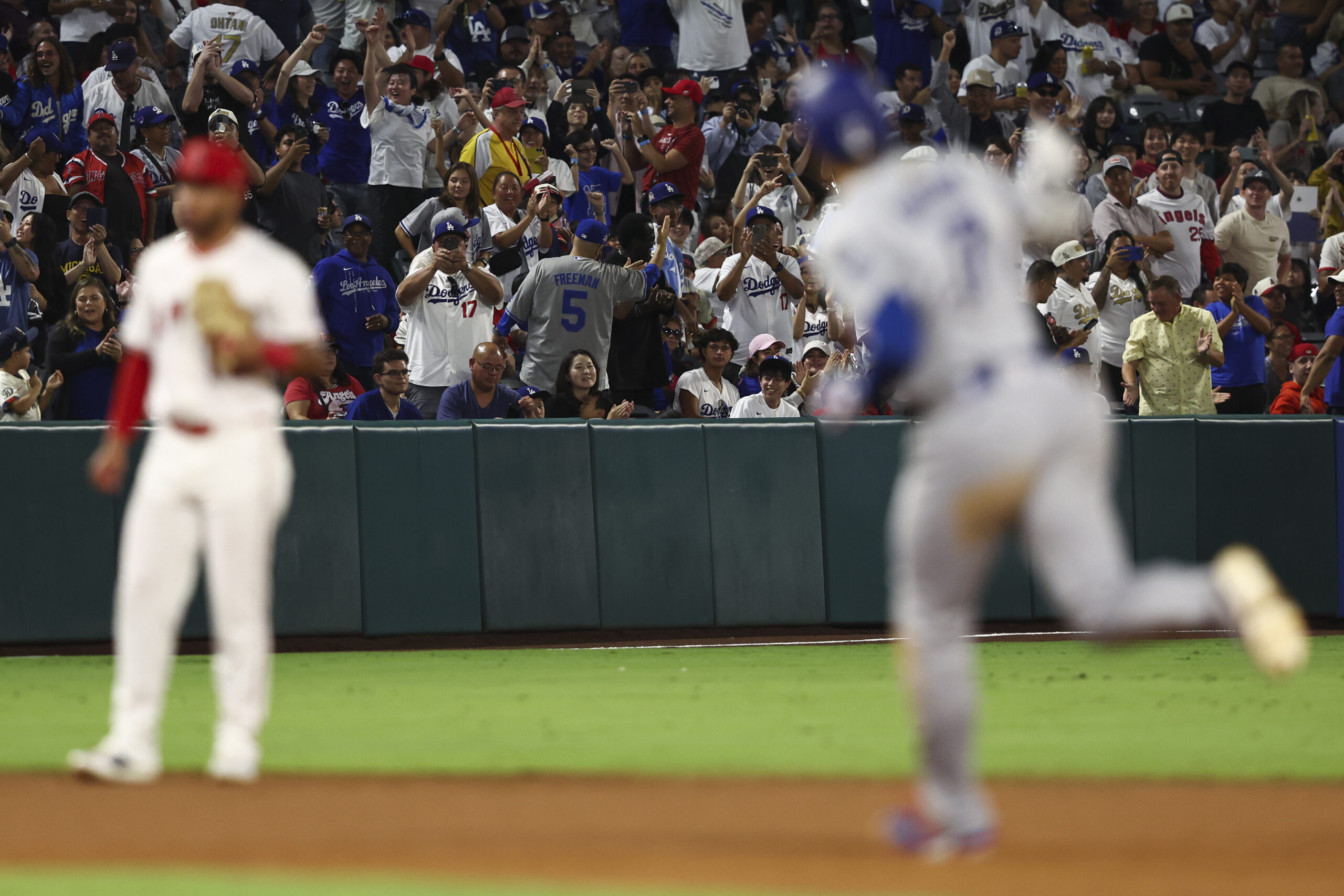 Fans cheer as Dodgers star Shohei Ohtani gestures while running...