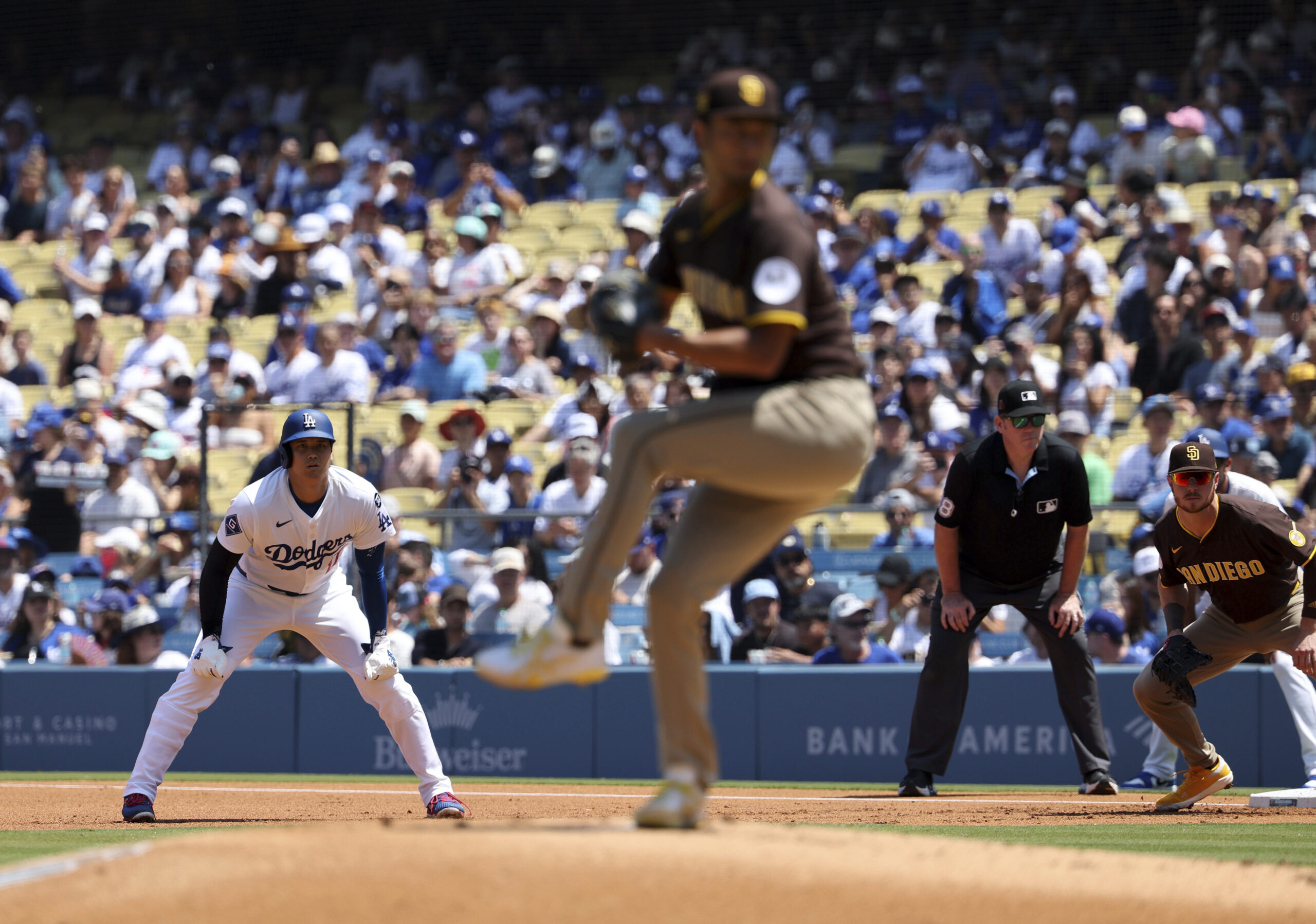 Dodgers star Shohei Ohtani, left, leads off of first base...