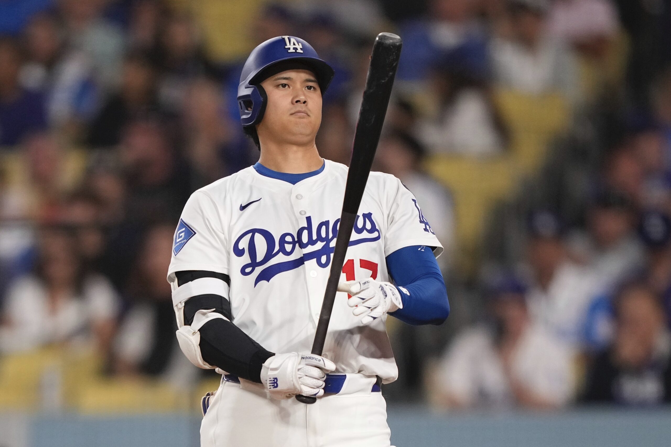 Dodgers star Shohei Ohtani checks his bat as he steps...