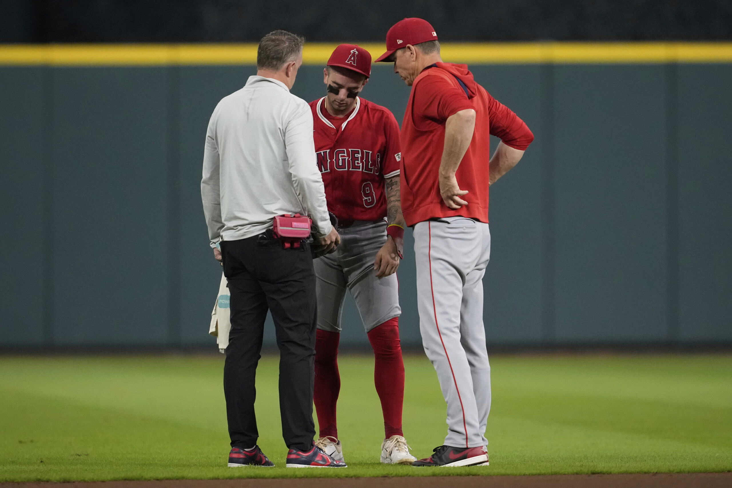 Angels shortstop Zach Neto, center, is checked out after reaching...