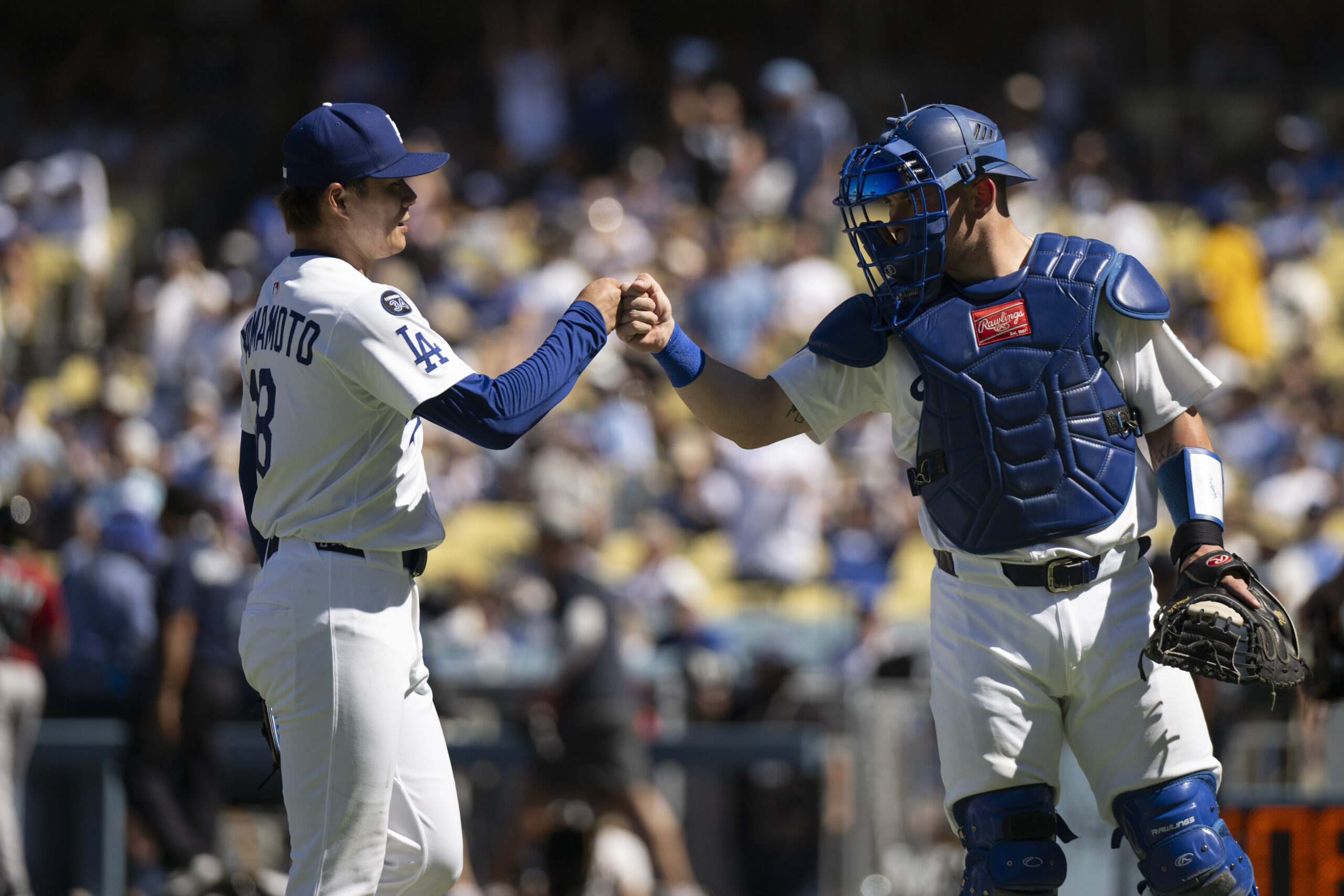 Dodgers starting pitcher Yoshinobu Yamamoto, left, bumps his fist with...