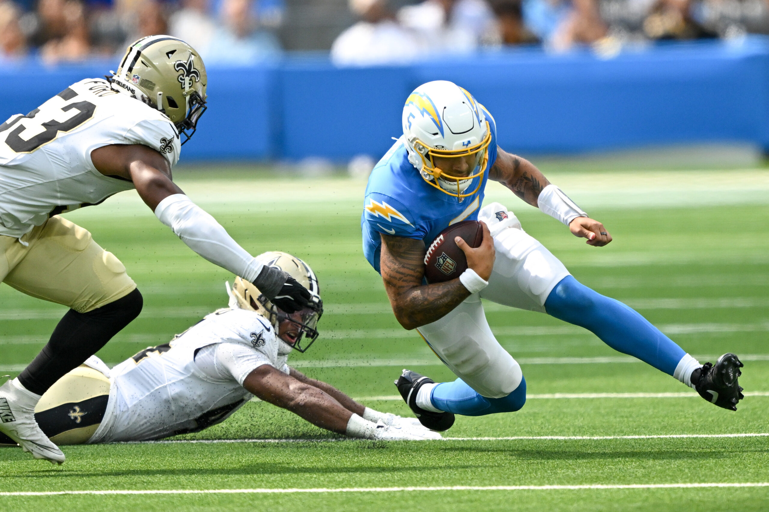 The Chargers QB Trey Lance, #5, outmaneuvers Saints Isaiah Stalbird,...