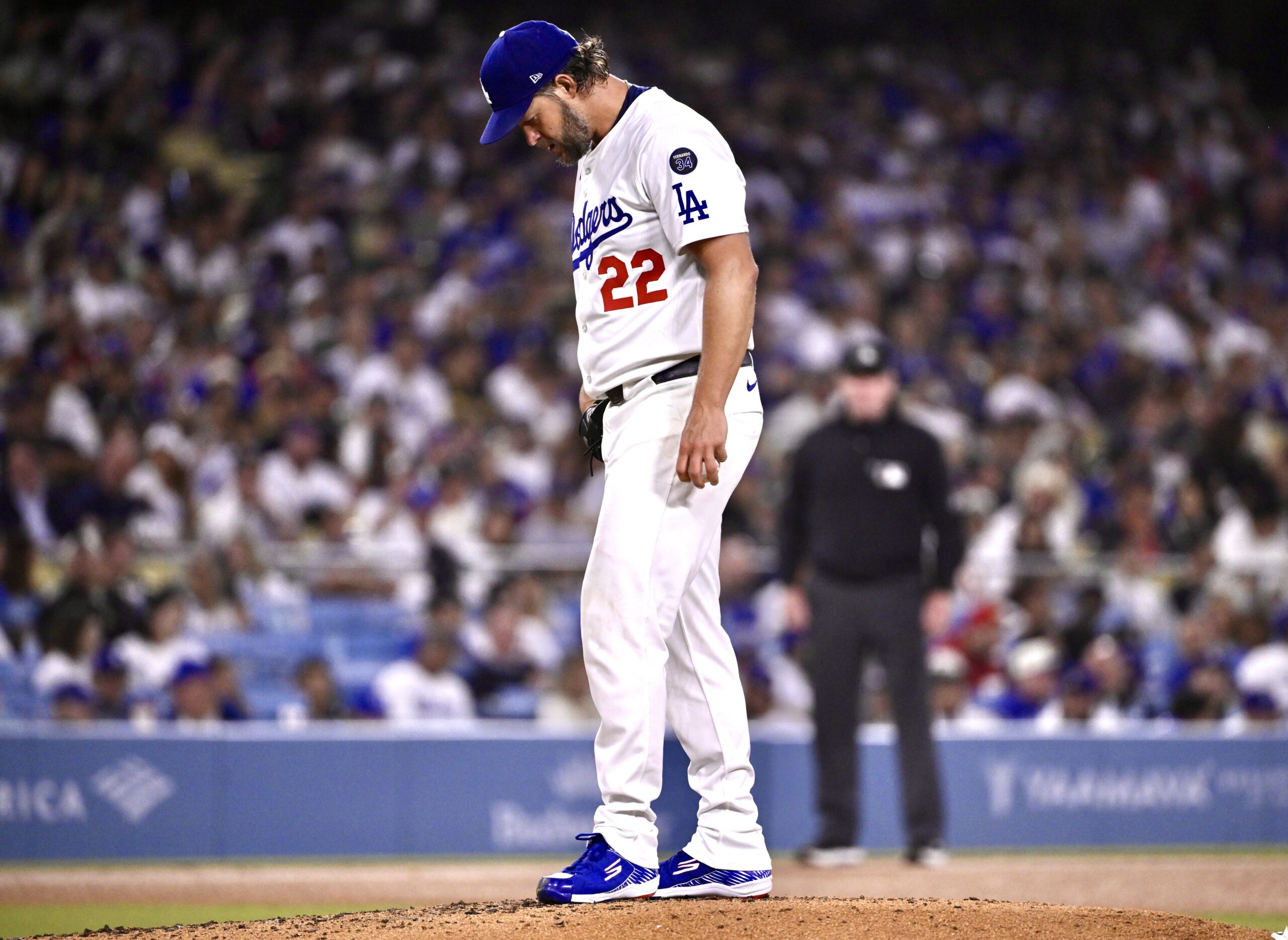 Dodgers starting pitcher Clayton Kershaw looks down at the mound...