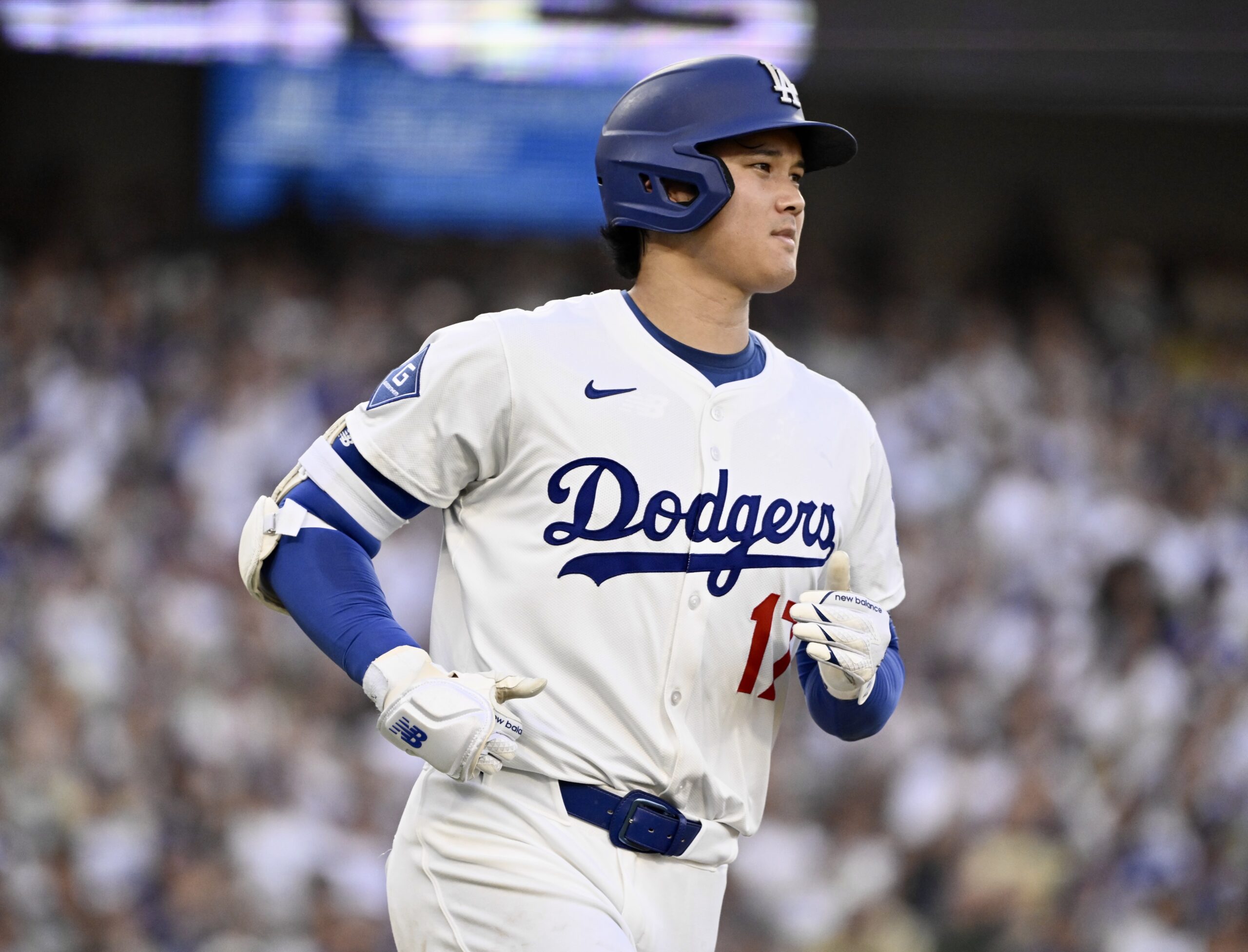 Dodgers star Shohei Ohtani runs to first base after hitting...