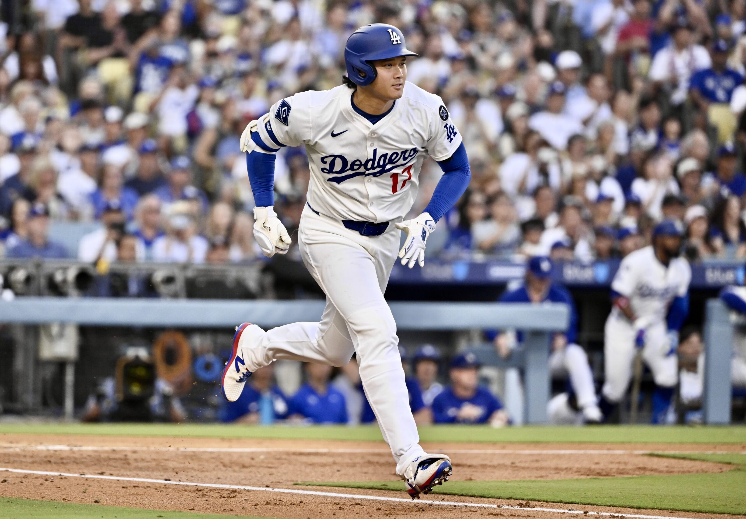 Dodgers star Shohei Ohtani runs to first base after hitting...