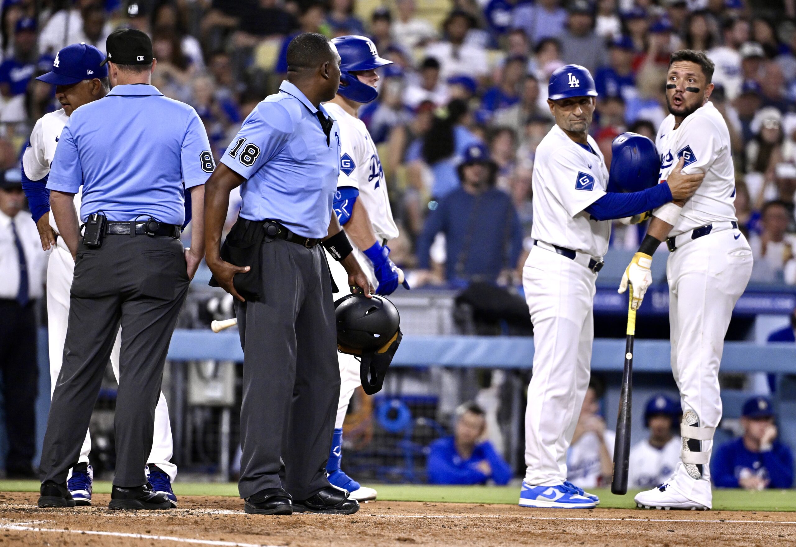 The Dodgers’ Miguel Rojas, right, is held back by third...