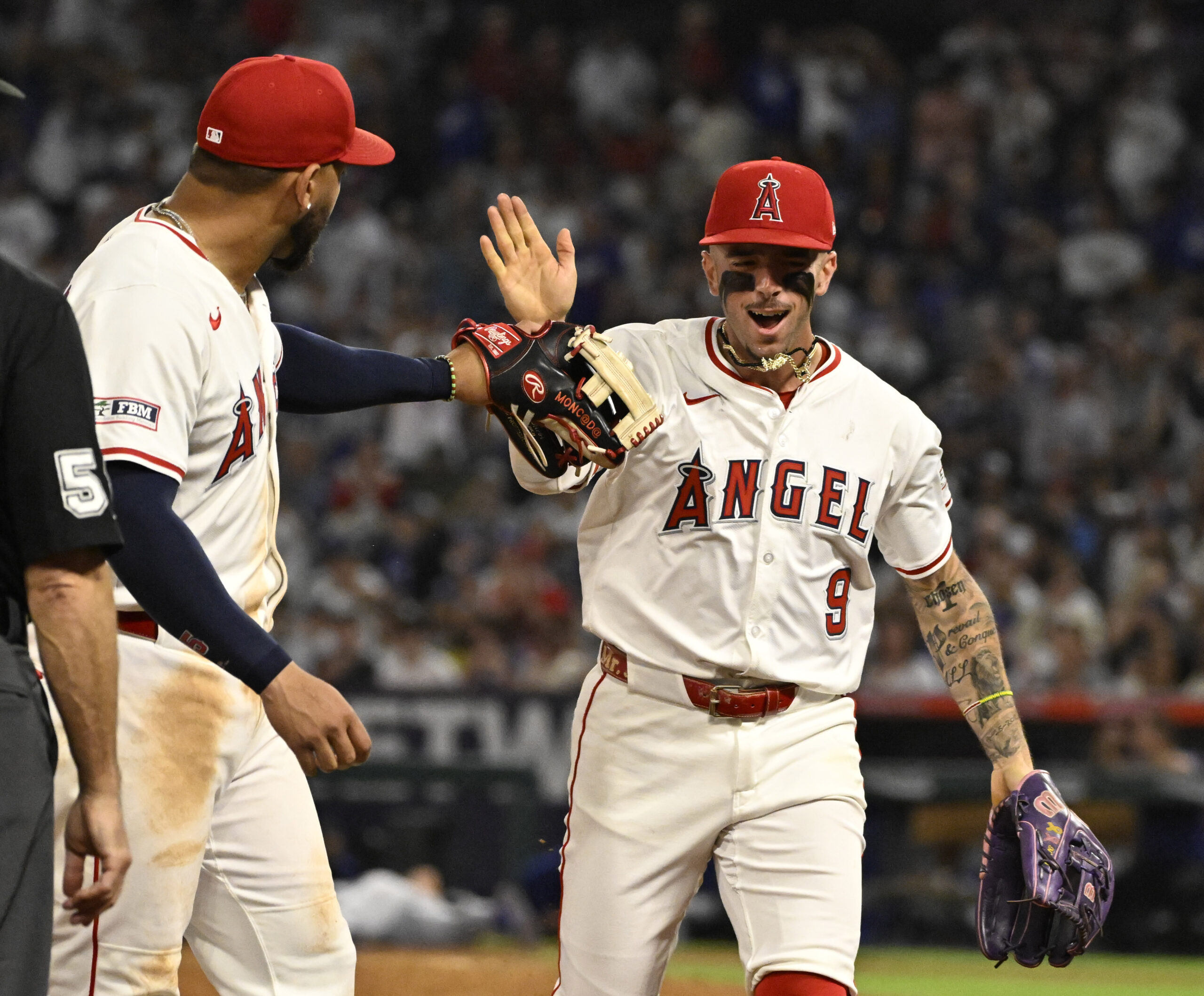 Angels shortstop Zach Neto, right, high-fives third baseman Yoán Moncada...