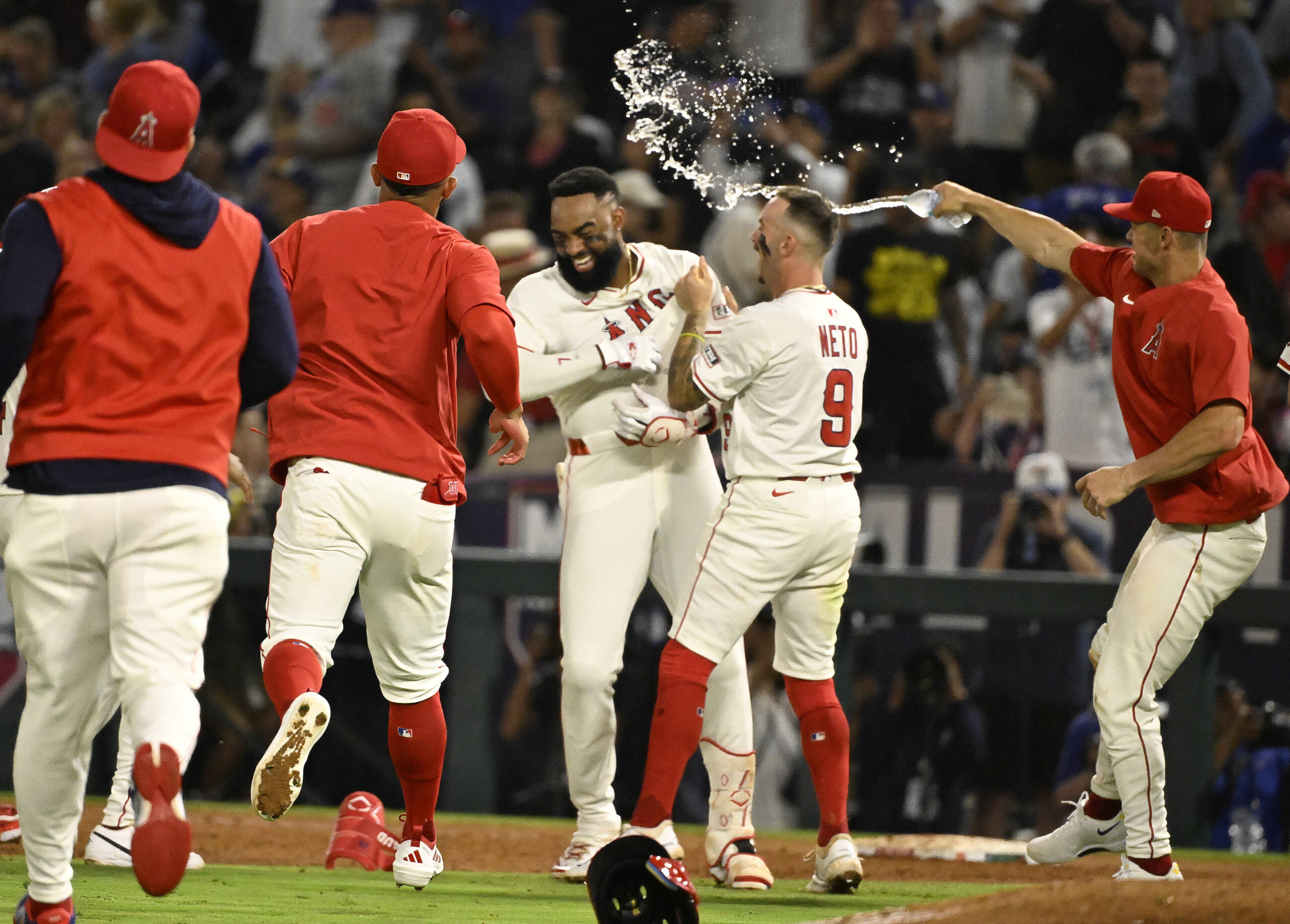 The Angels’ Jo Adell, center, is mobbed by teammate Zach...
