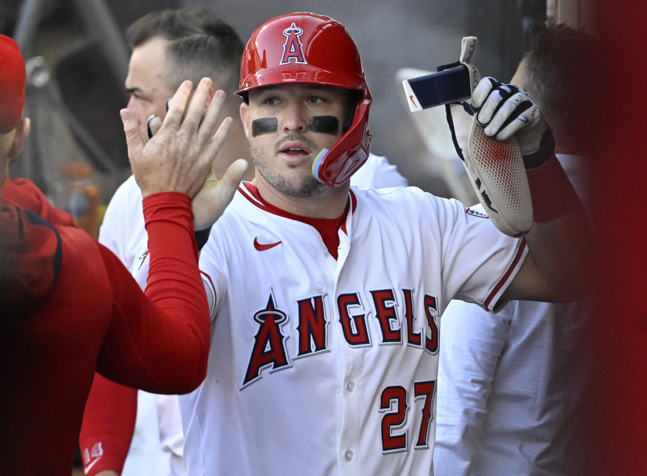 Angels star Mike Trout celebrates in the dugout after scoring...
