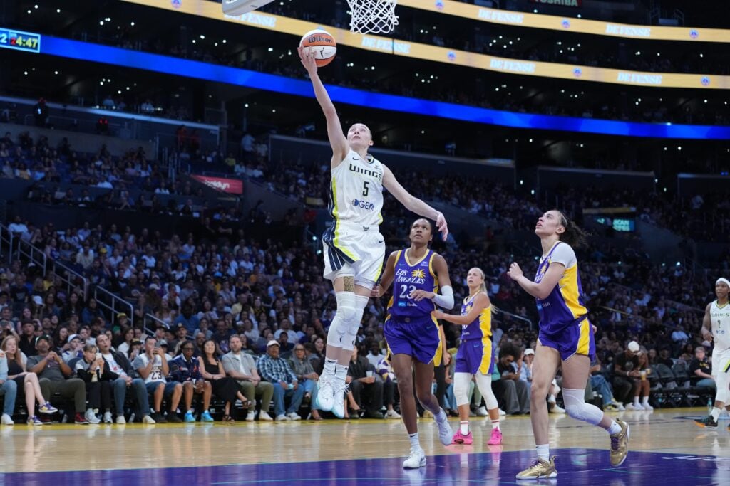 Aug 20, 2025; Los Angeles, California, USA; Dallas Wings guard Paige Bueckers (5) shoots the ball against LA Sparks forward Dearica Hamby (5) and forward Azura Stevens (23) in the first half at Crypto.com Arena. Mandatory Credit: Kirby Lee-Imagn Images