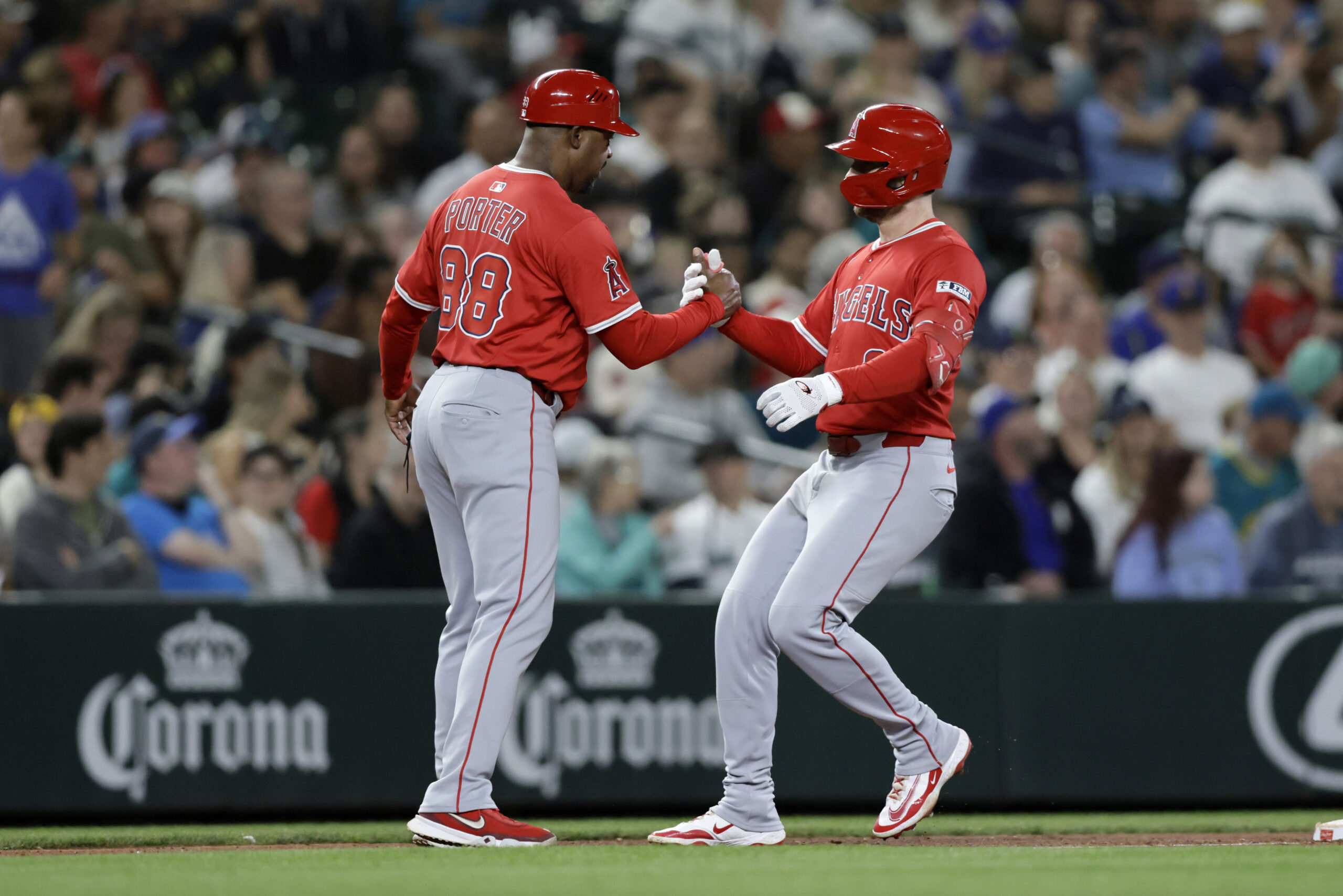 Angels’ Taylor Ward, right, is greeted by third base coach...