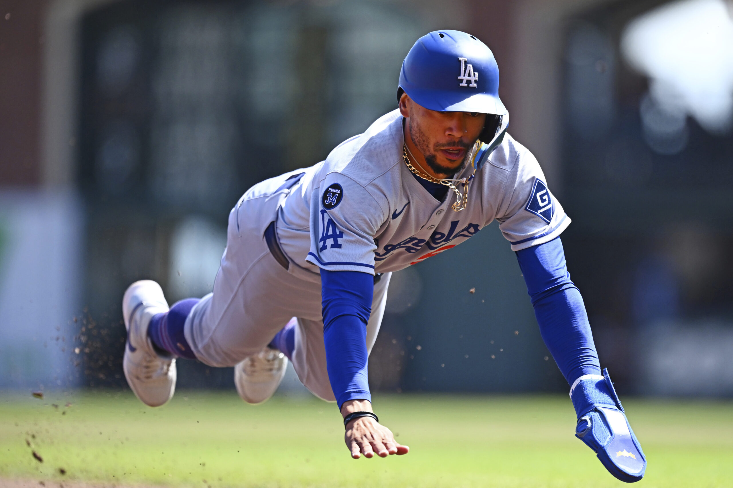 Dodgers’ Mookie Betts (50) dives into third base on a...