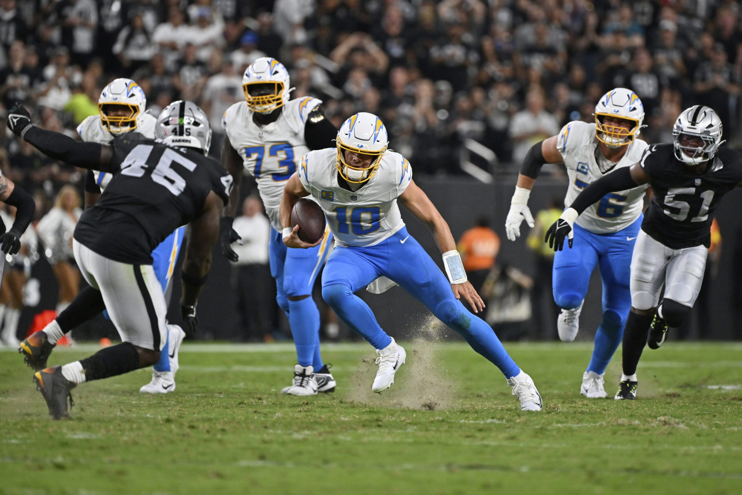 Chargers quarterback Justin Herbert runs with the ball against the...