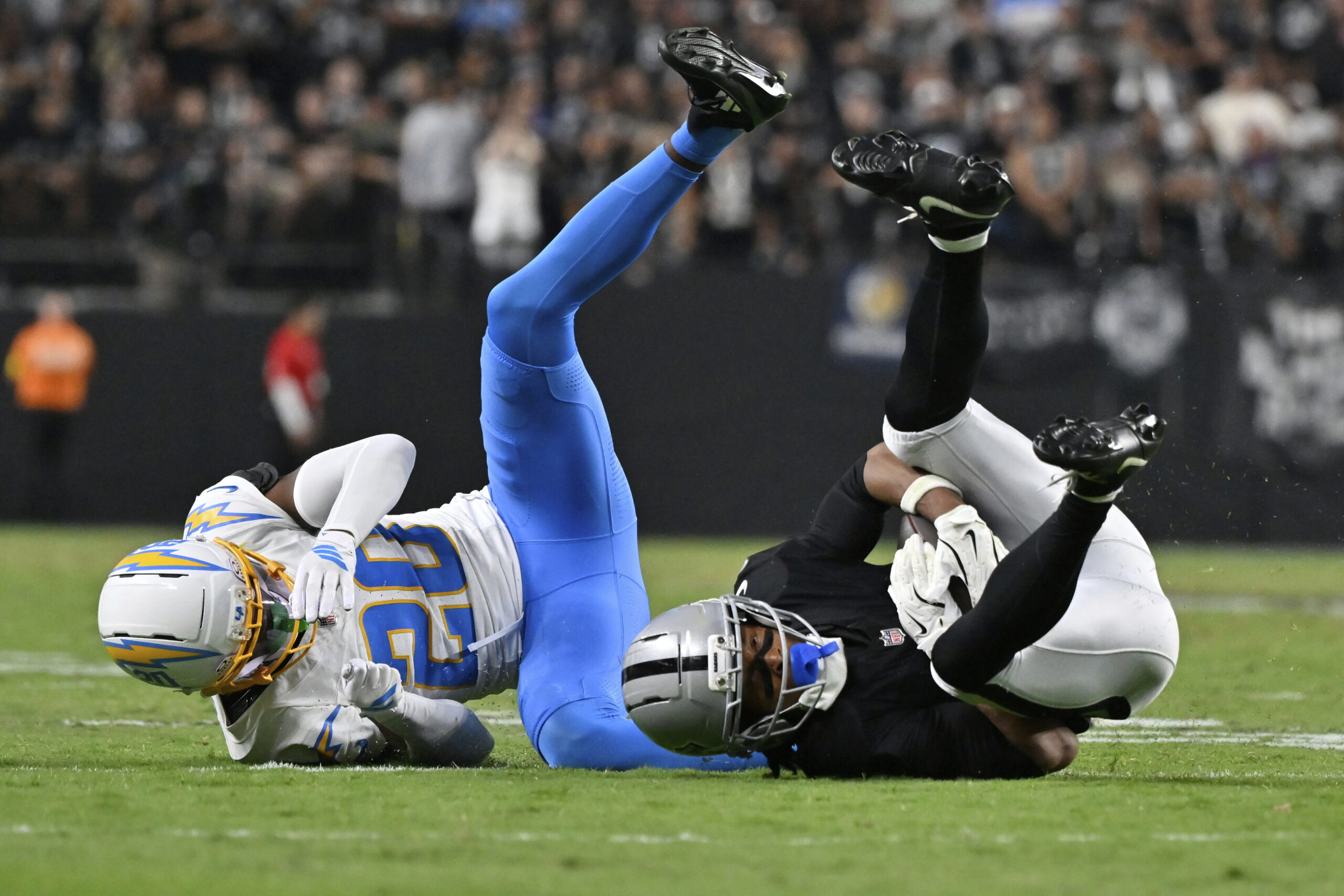 Chargers cornerback Cam Hart, left, tackles Las Vegas Raiders wide...
