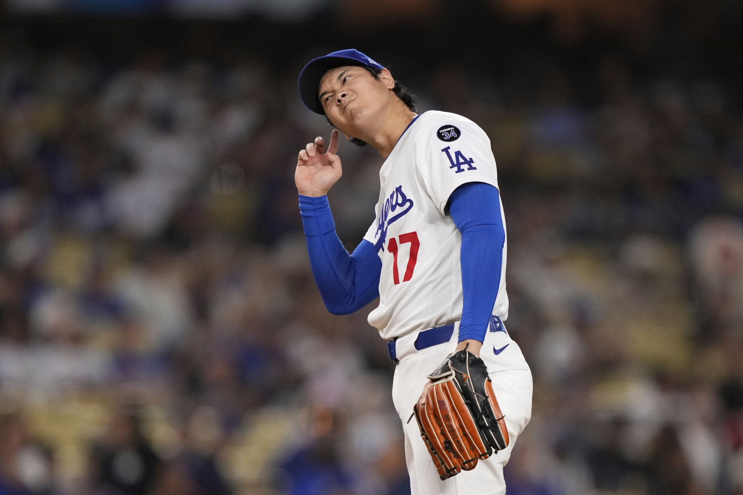Dodgers starting pitcher Shohei Ohtani touches his ear as gets...