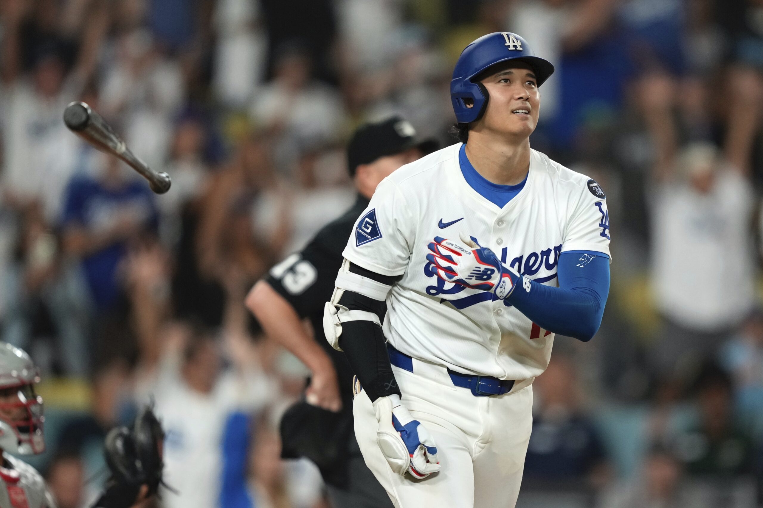 Dodgers star Shohei Ohtani tosses his bat as he watches...