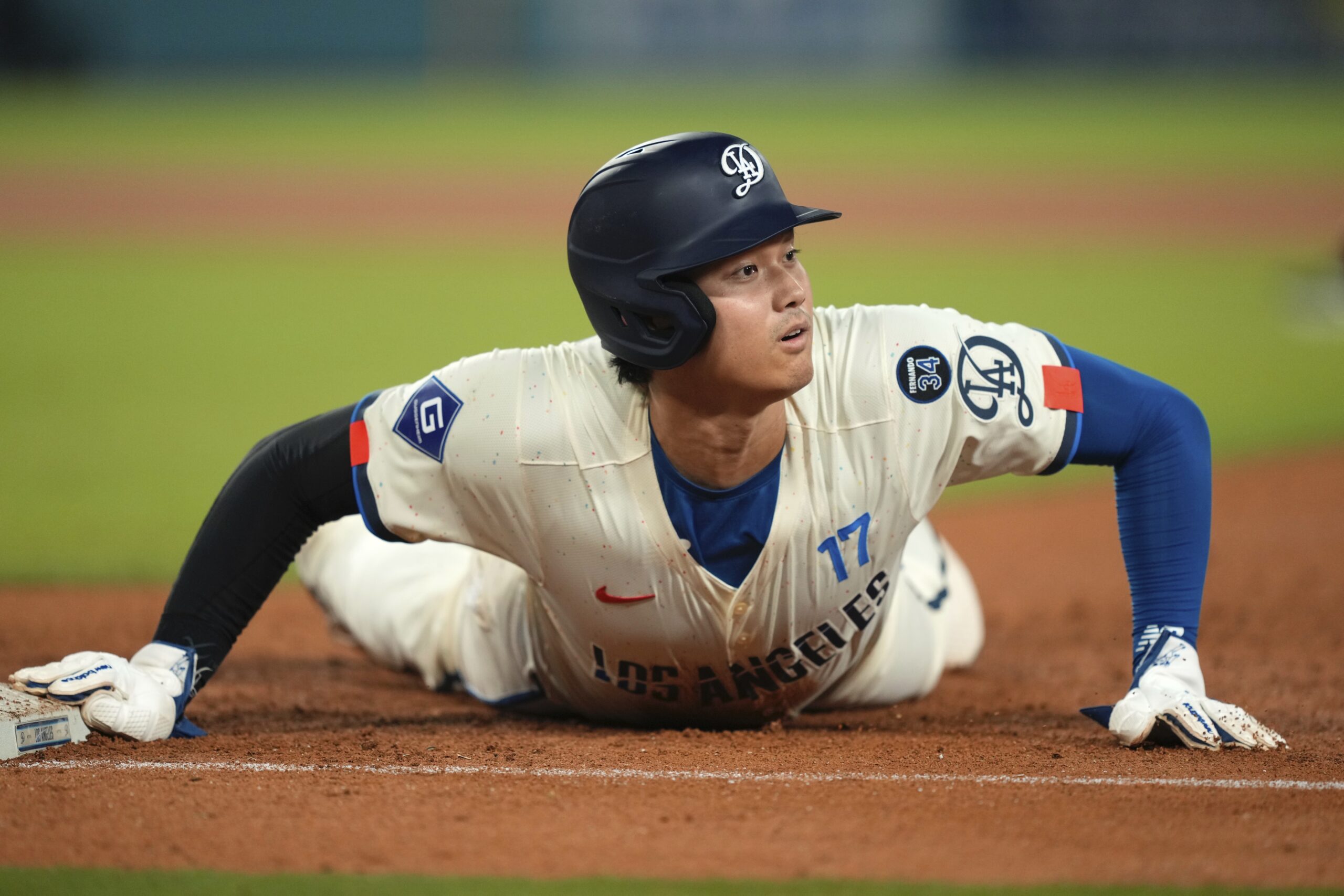 Dodgers’ Shohei Ohtani looks up after diving back to first...