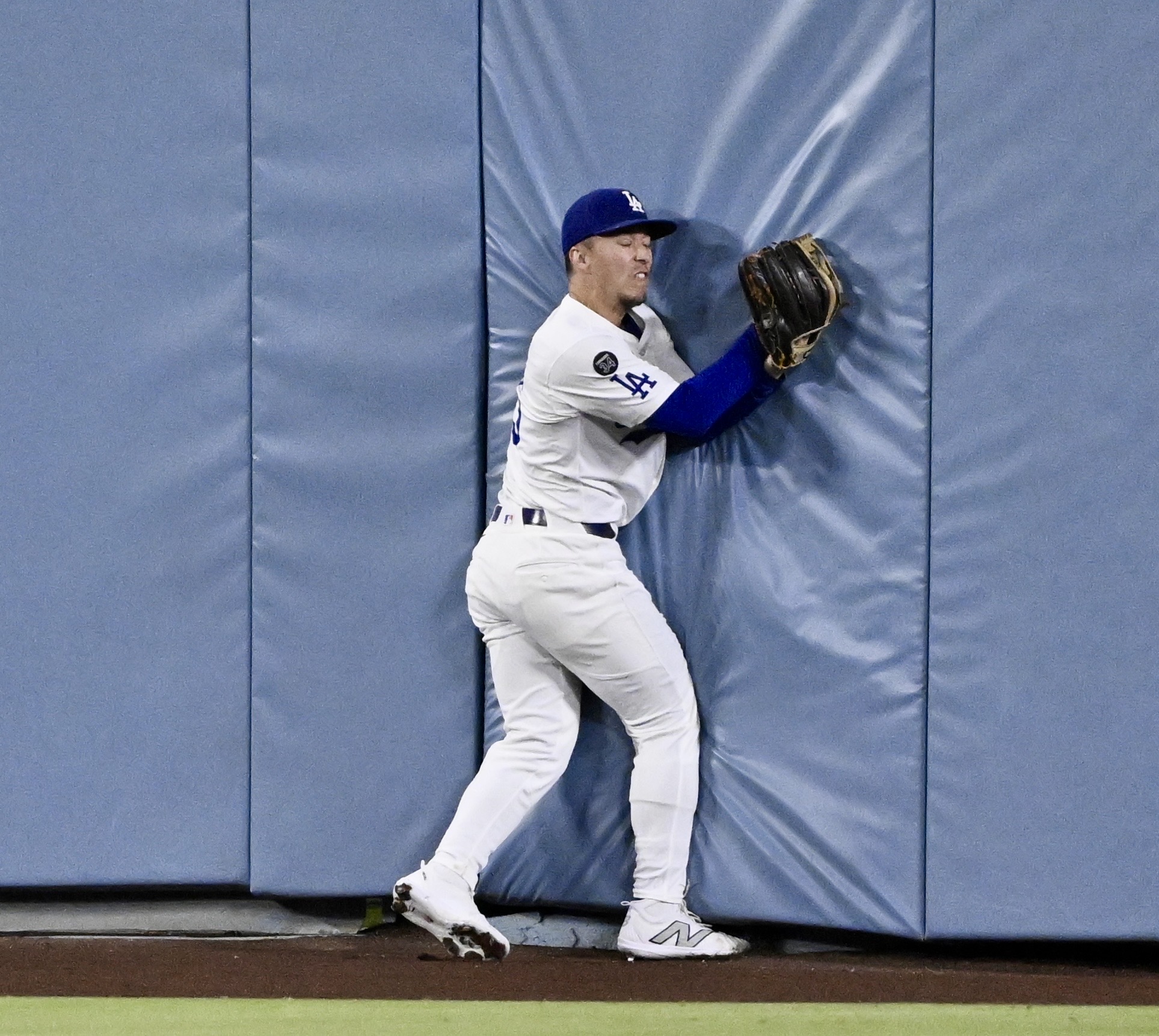 Dodgers center fielder Tommy Edman bumps into the padded outfield...