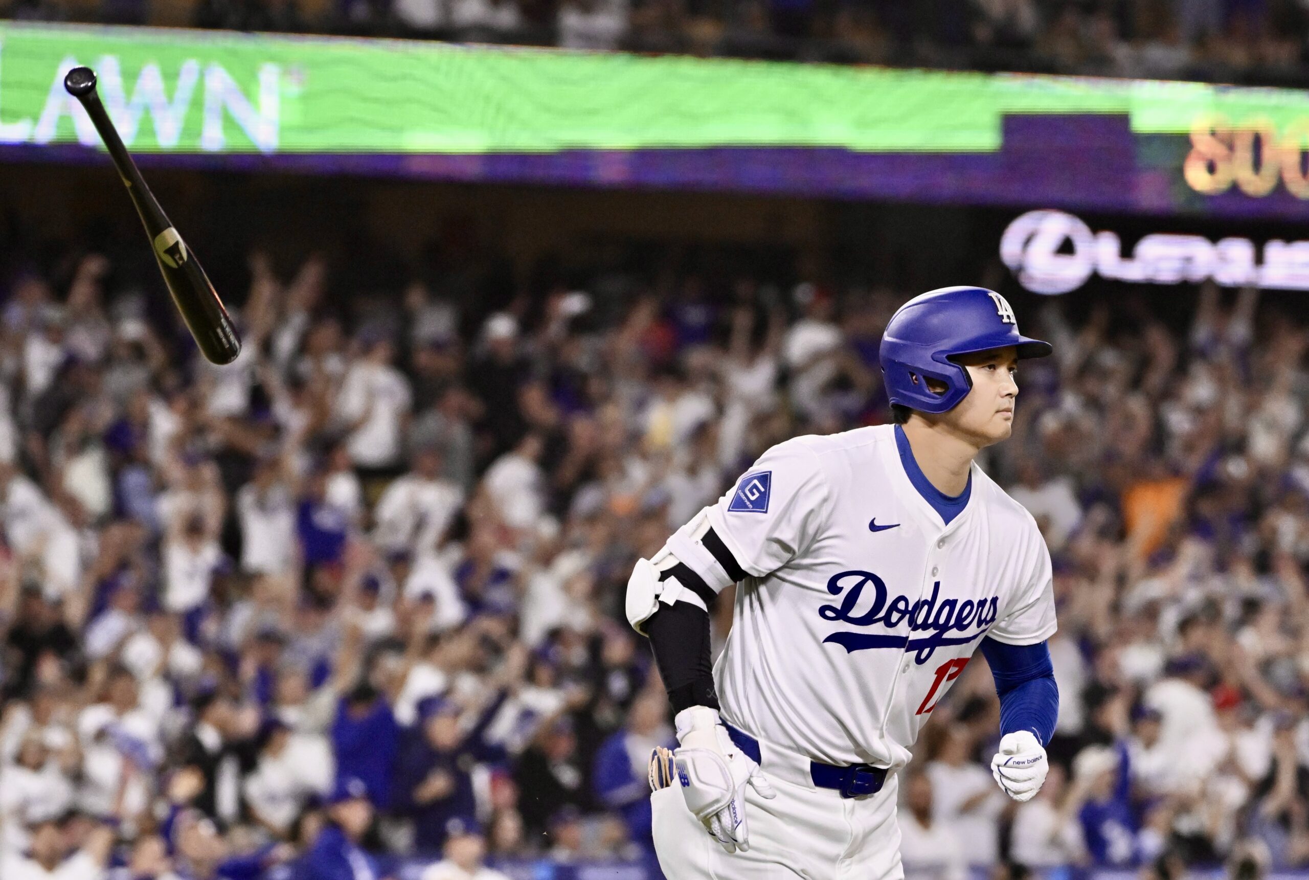 Dodgers star Shohei Ohtani tosses his bat as he begins...