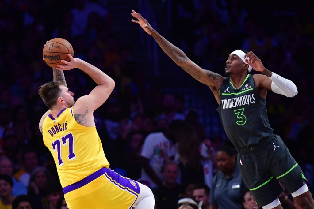 Apr 30, 2025; Los Angeles, California, USA; Los Angeles Lakers guard Luka Doncic (77) shoots against Minnesota Timberwolves forward Jaden McDaniels (3) during the second half in game five of first round for the 2025 NBA Playoffs at Crypto.com Arena. Mandatory Credit: Gary A. Vasquez-Imagn Images