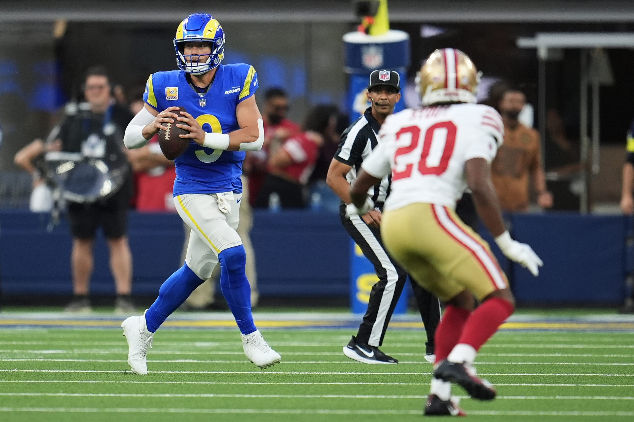 Rams quarterback Matthew Stafford, left, rolls out to pass as...