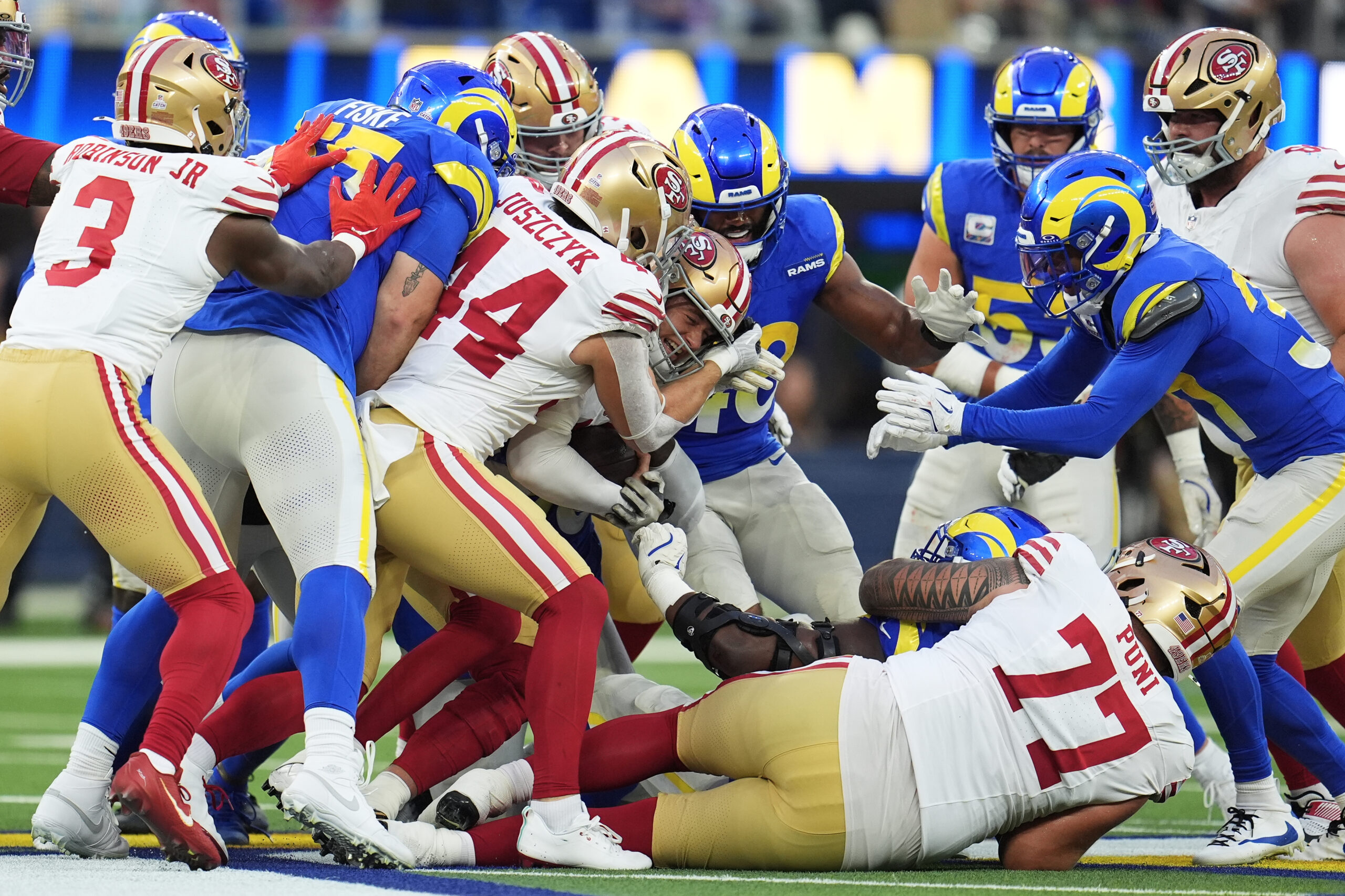 San Francisco 49ers quarterback Mac Jones, middle, runs for a...