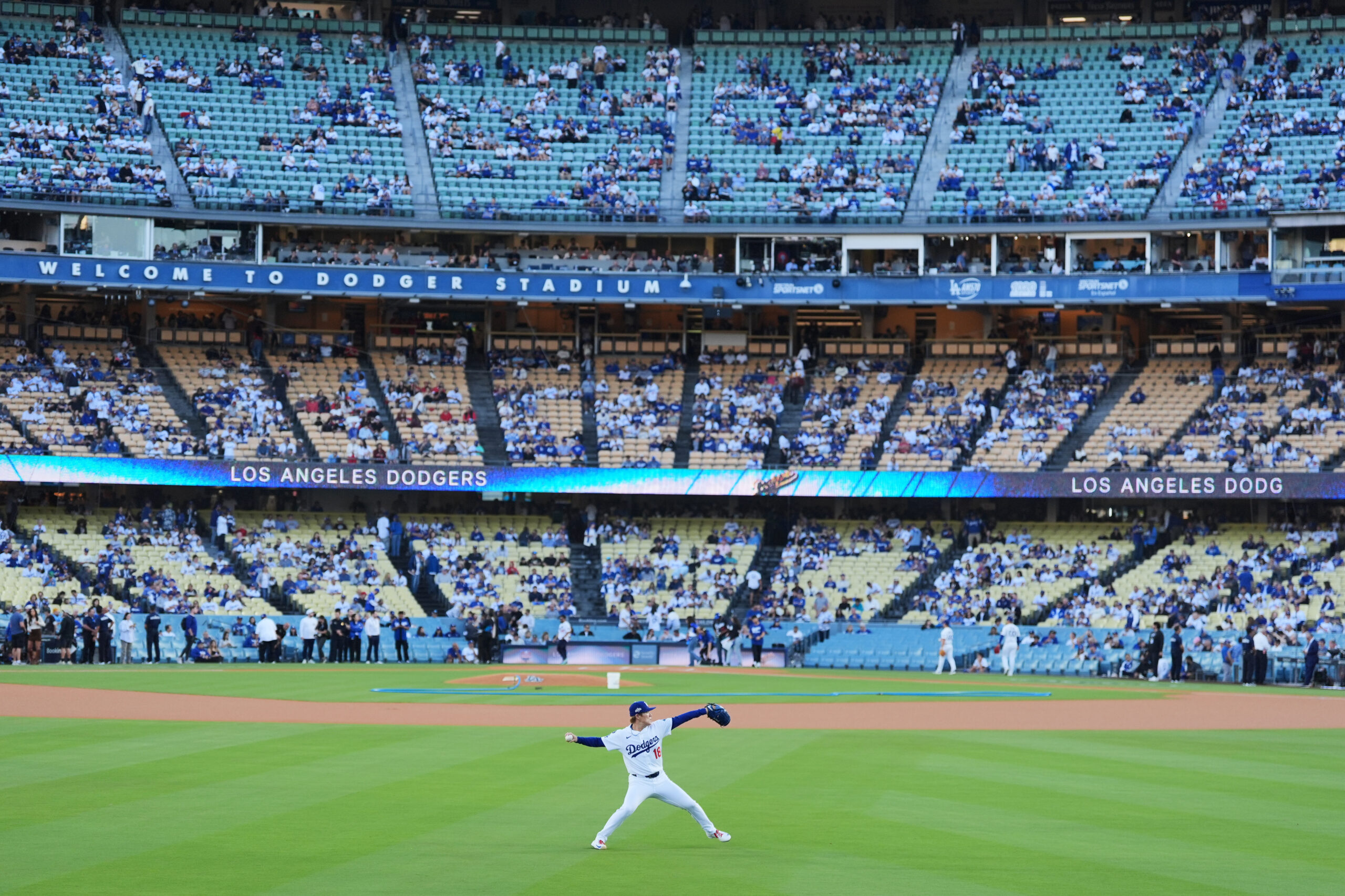 Dodgers starting pitcher Yoshinobu Yamamoto warms up in the outfield...