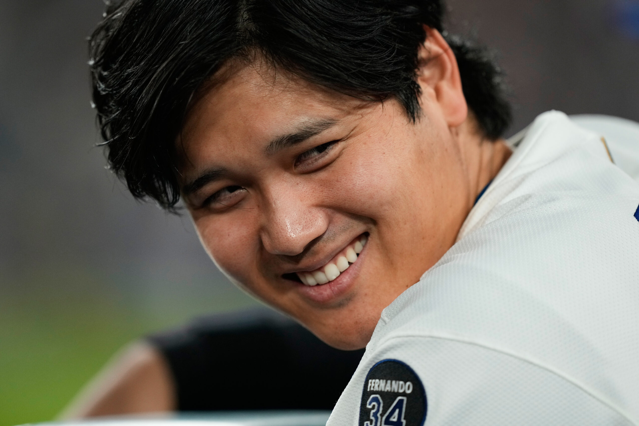 Dodgers star Shohei Ohtani smiles in the dugout during the...