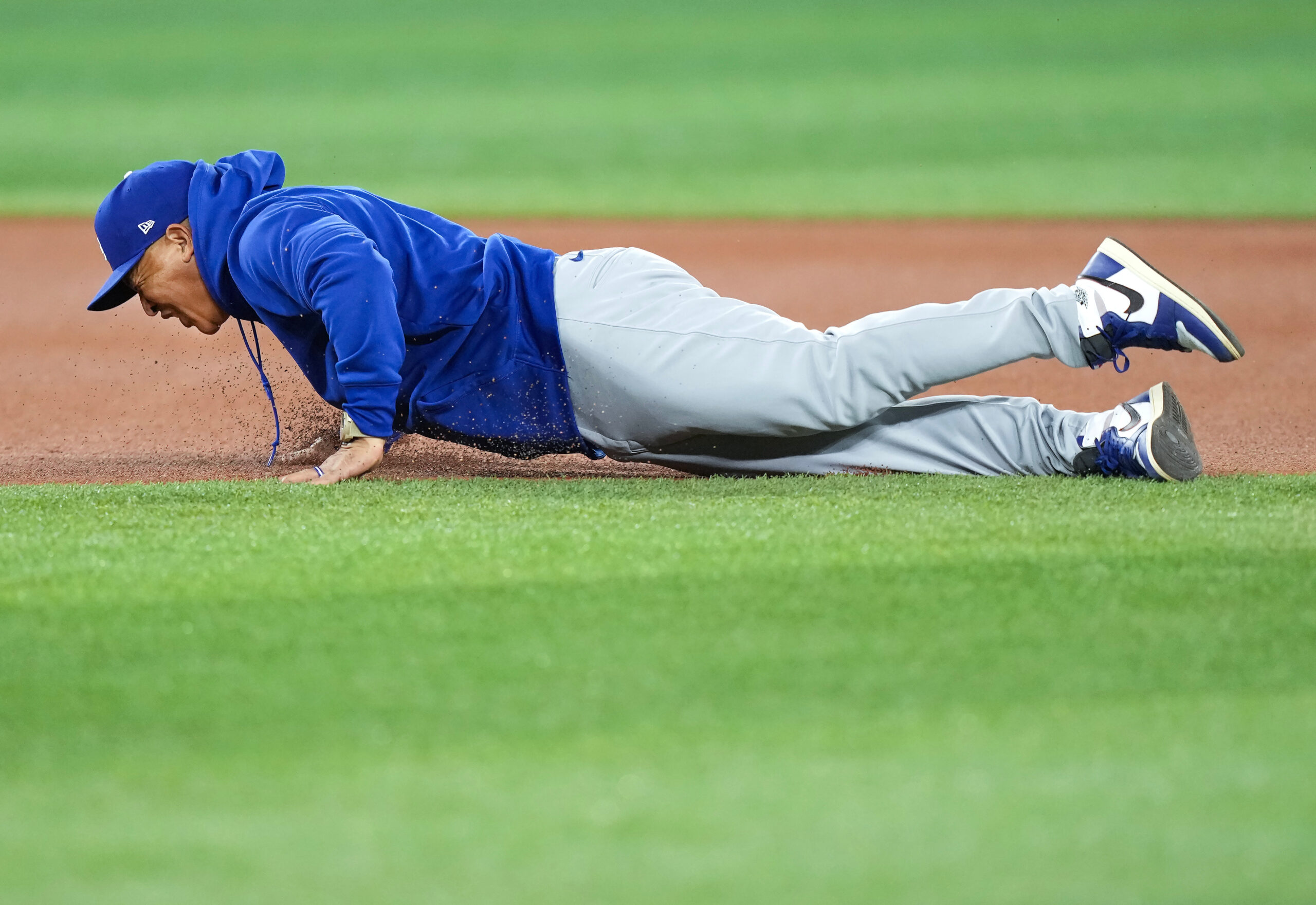 Dodgers manager Dave Roberts wipes out and falls to the...