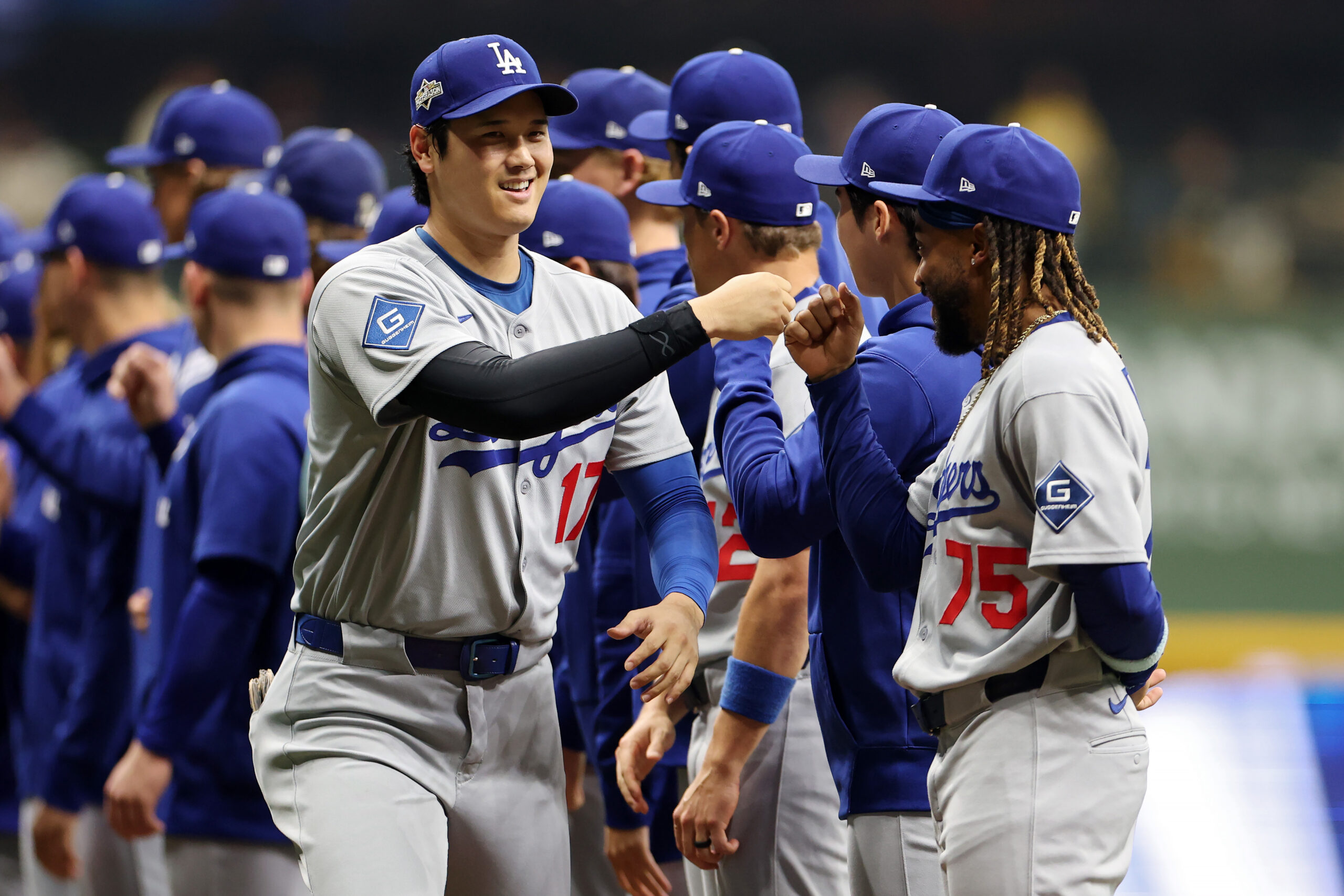Dodgers star Shohei Ohtani, left, greets teammates before Game 1...
