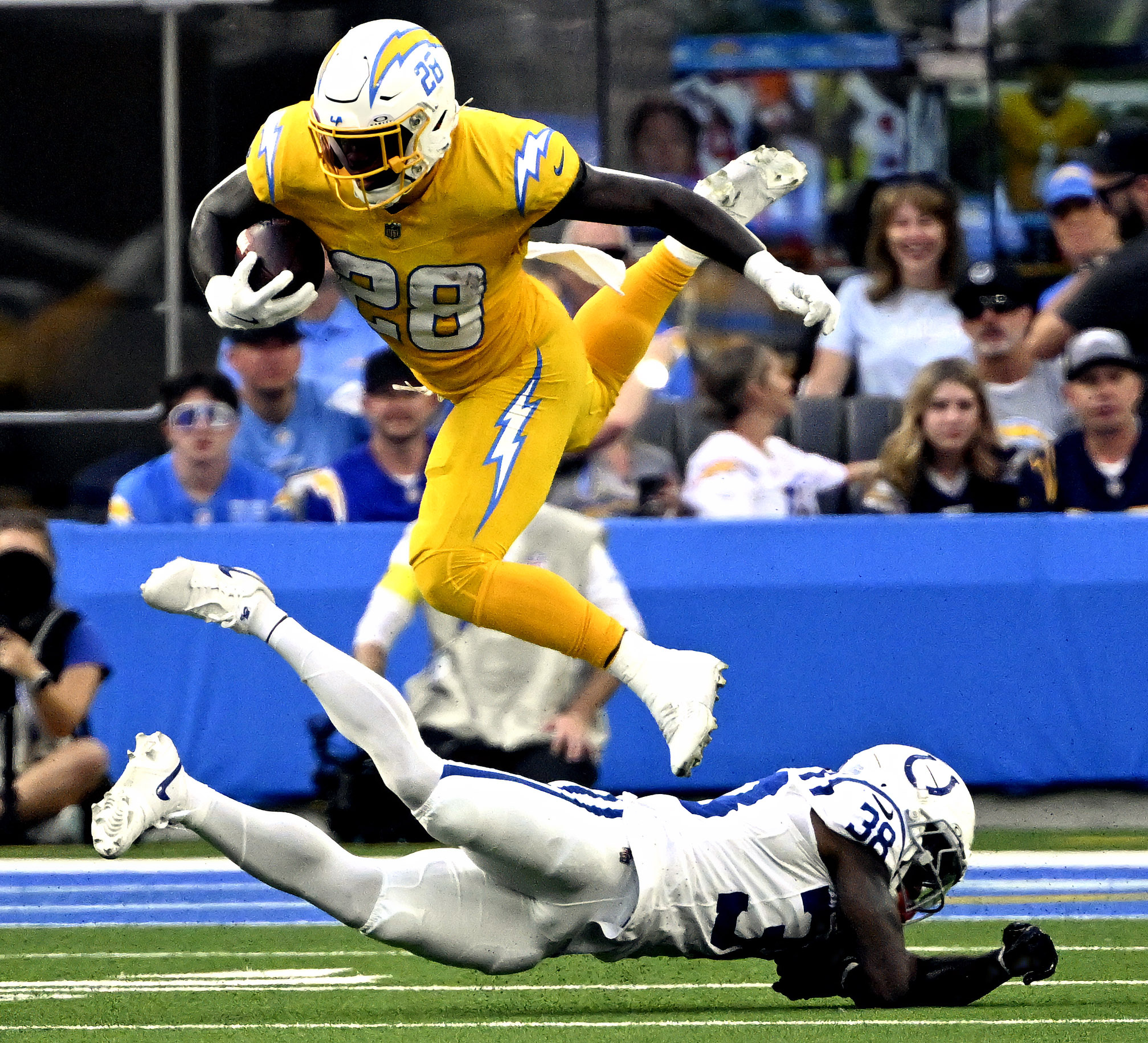 Running back Hassan Haskins #28 of the Chargers leaps over...