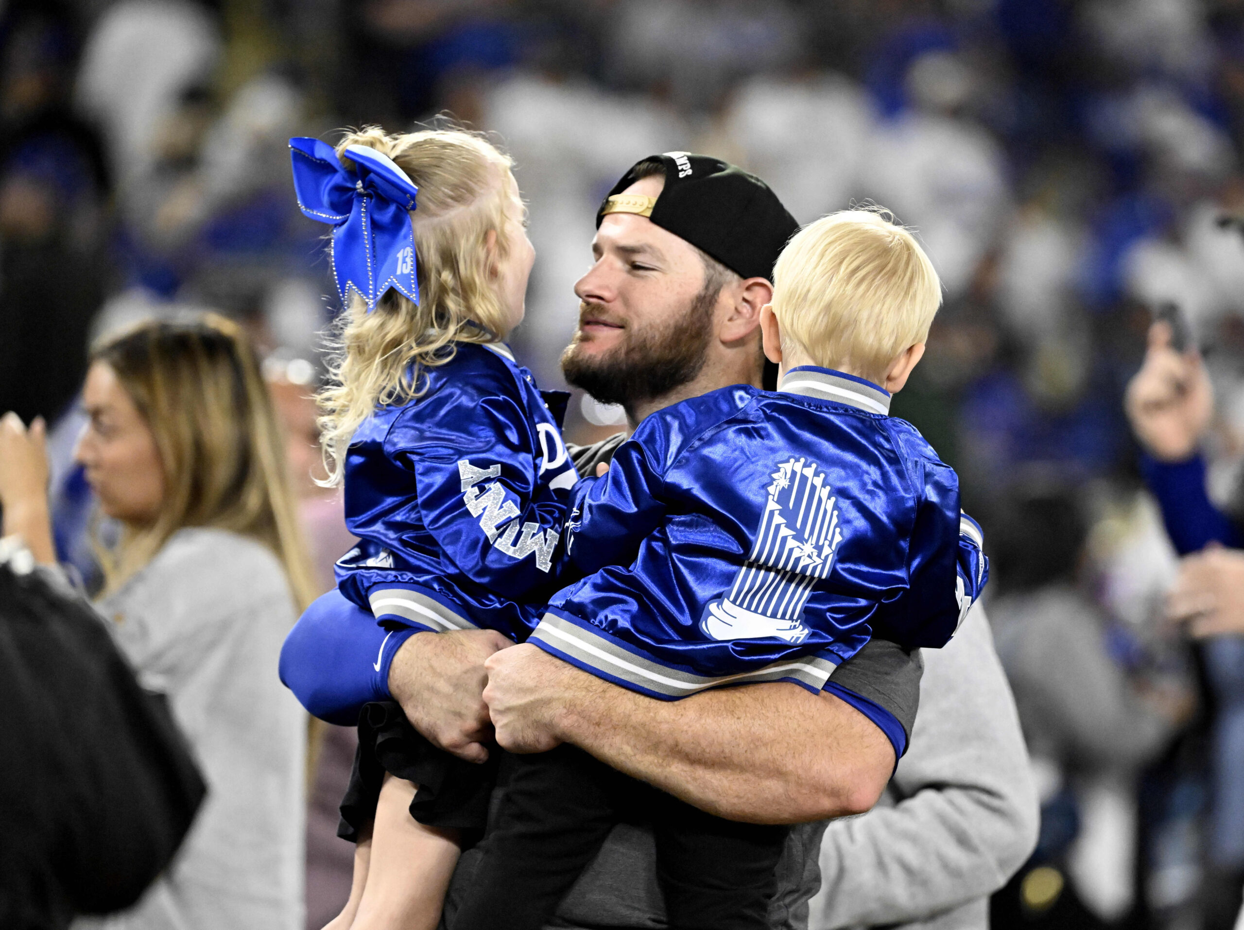 Max Muncy of the Los Angeles Dodgers hugs his children...